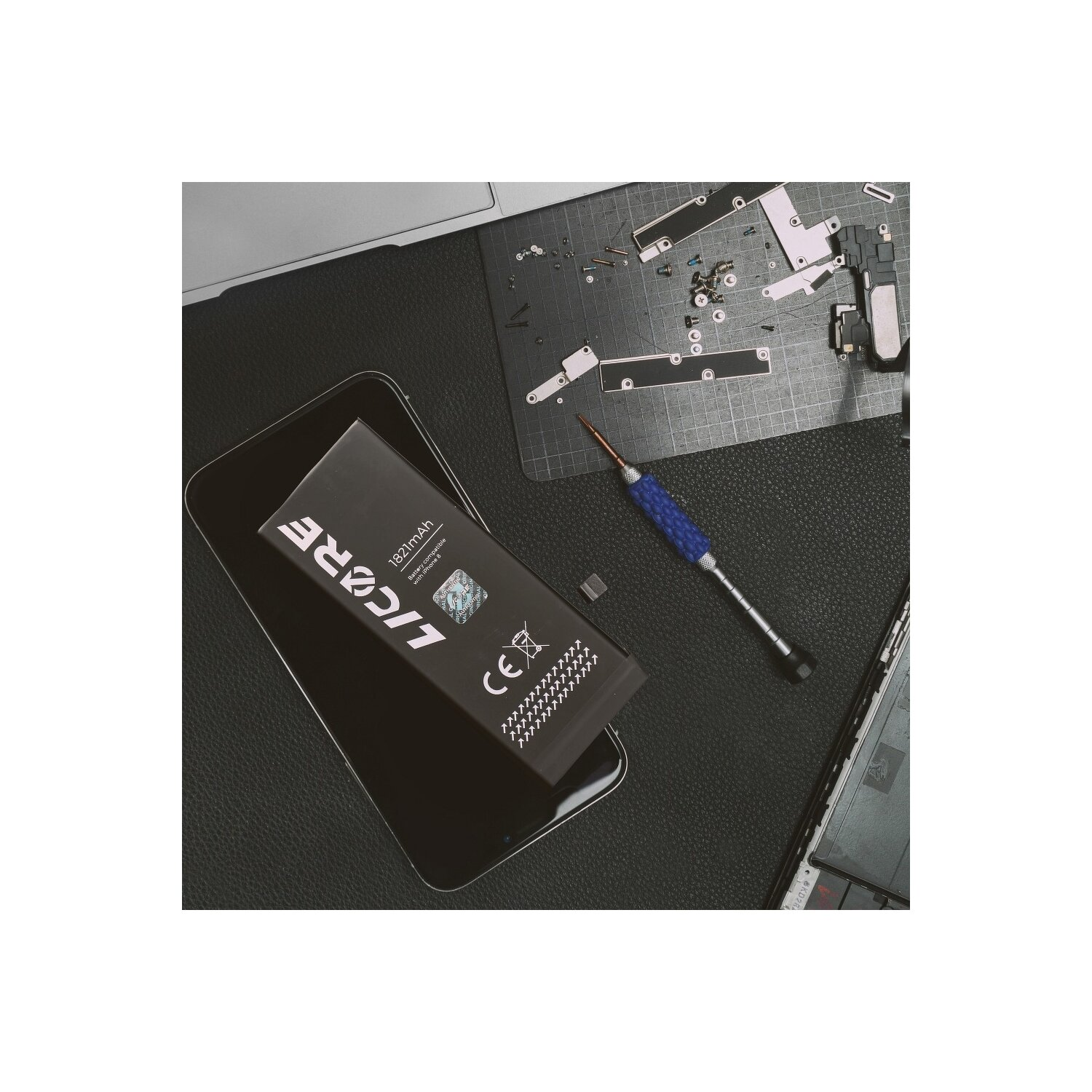 Telefon mit LiCORE-Akku, Bildschirm und Werkzeugen auf schwarzer Oberfläche.