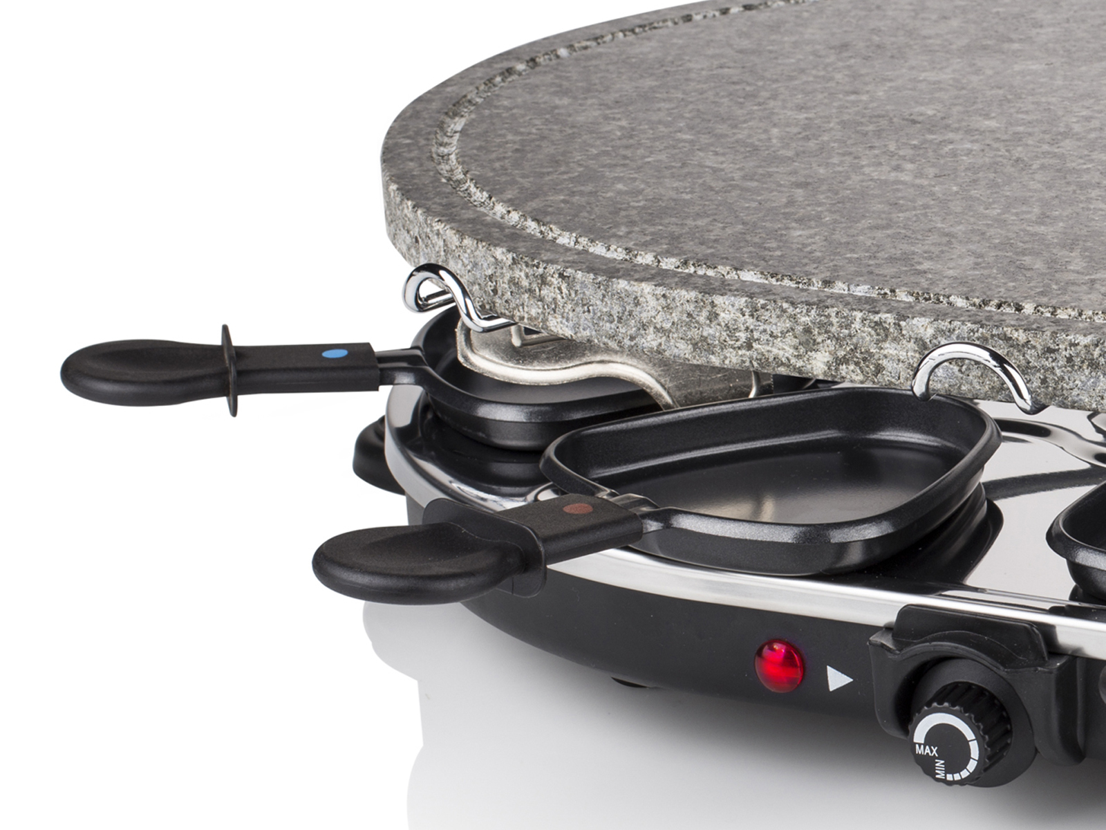 Nahaufnahme eines Raclette-Grills mit zwei Pfannen und einer Kochfläche aus Stein. Schwarze Griffe und rotes Licht.