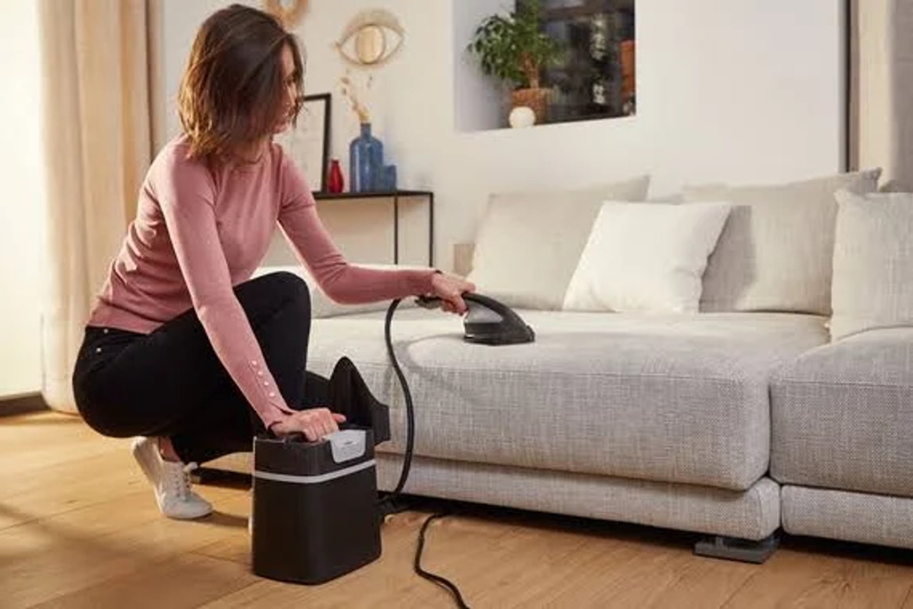 Donna che usa un vaporizzatore su un divano. Vaporizzatore e cavo neri.