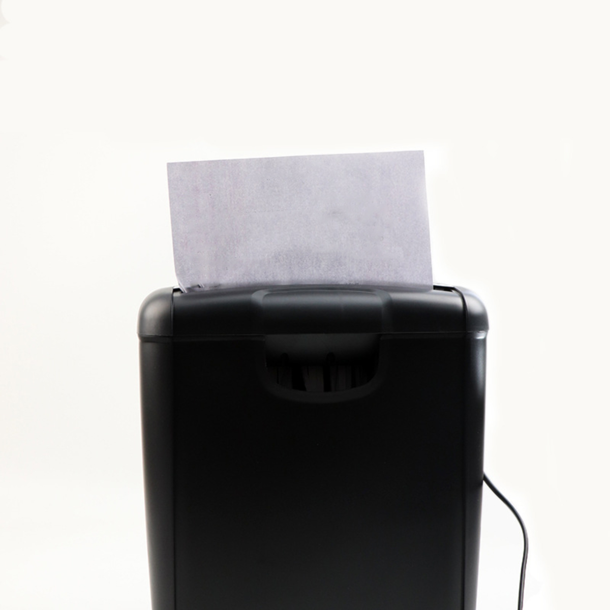 Ein schwarzer Aktenvernichter mit einem Papierstück, das hineingeführt wird, auf weißem Hintergrund.