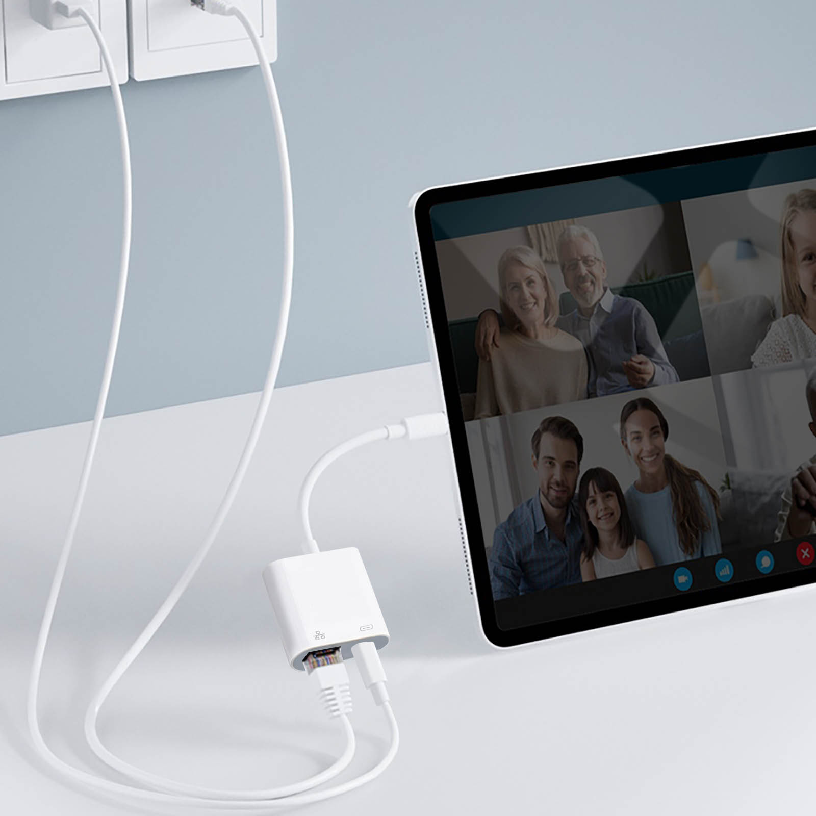 Adaptateur blanc avec deux ports RJ45 et un câble blanc connecté à une tablette avec appel vidéo.