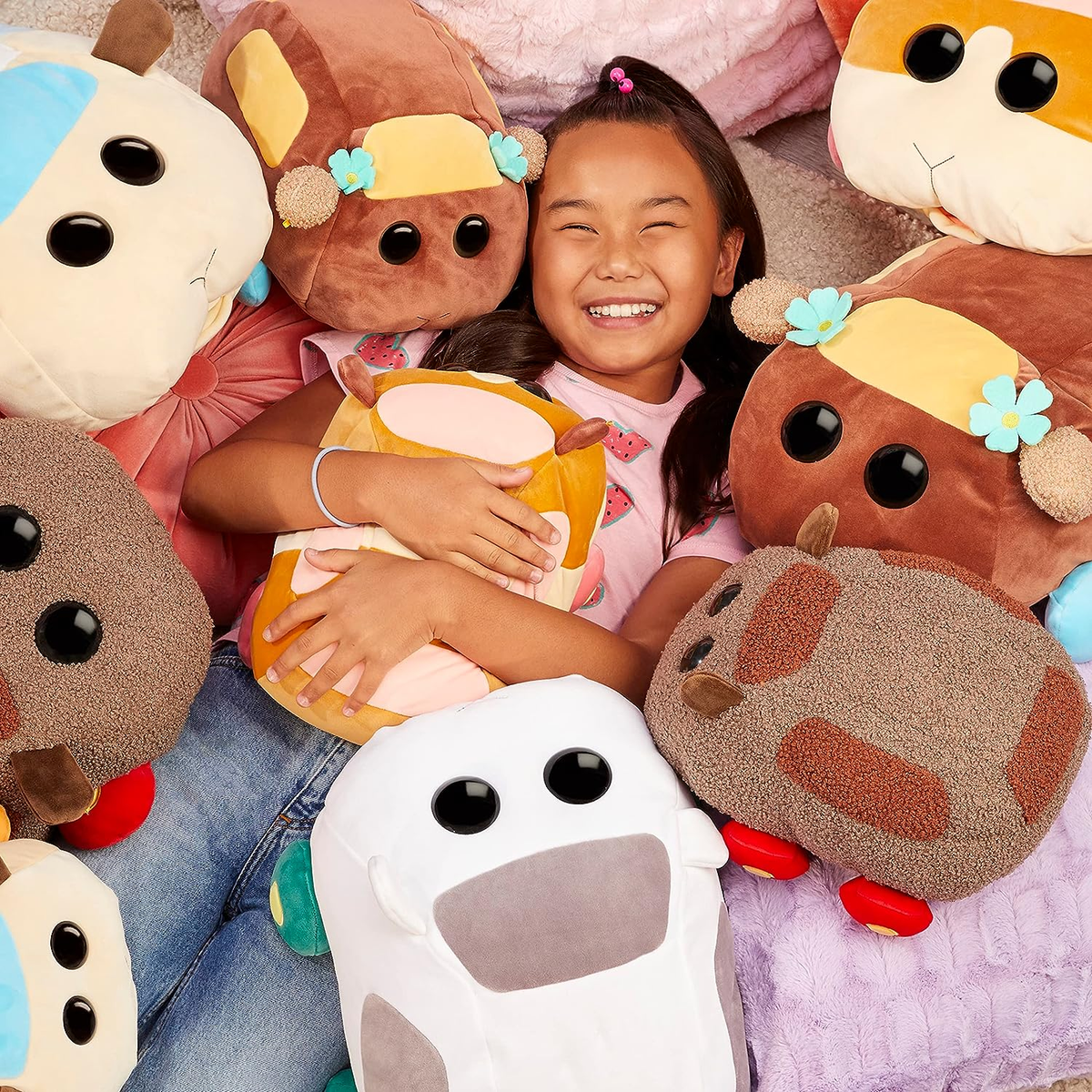 Ragazza circondata da peluche a forma di auto, sorridente.