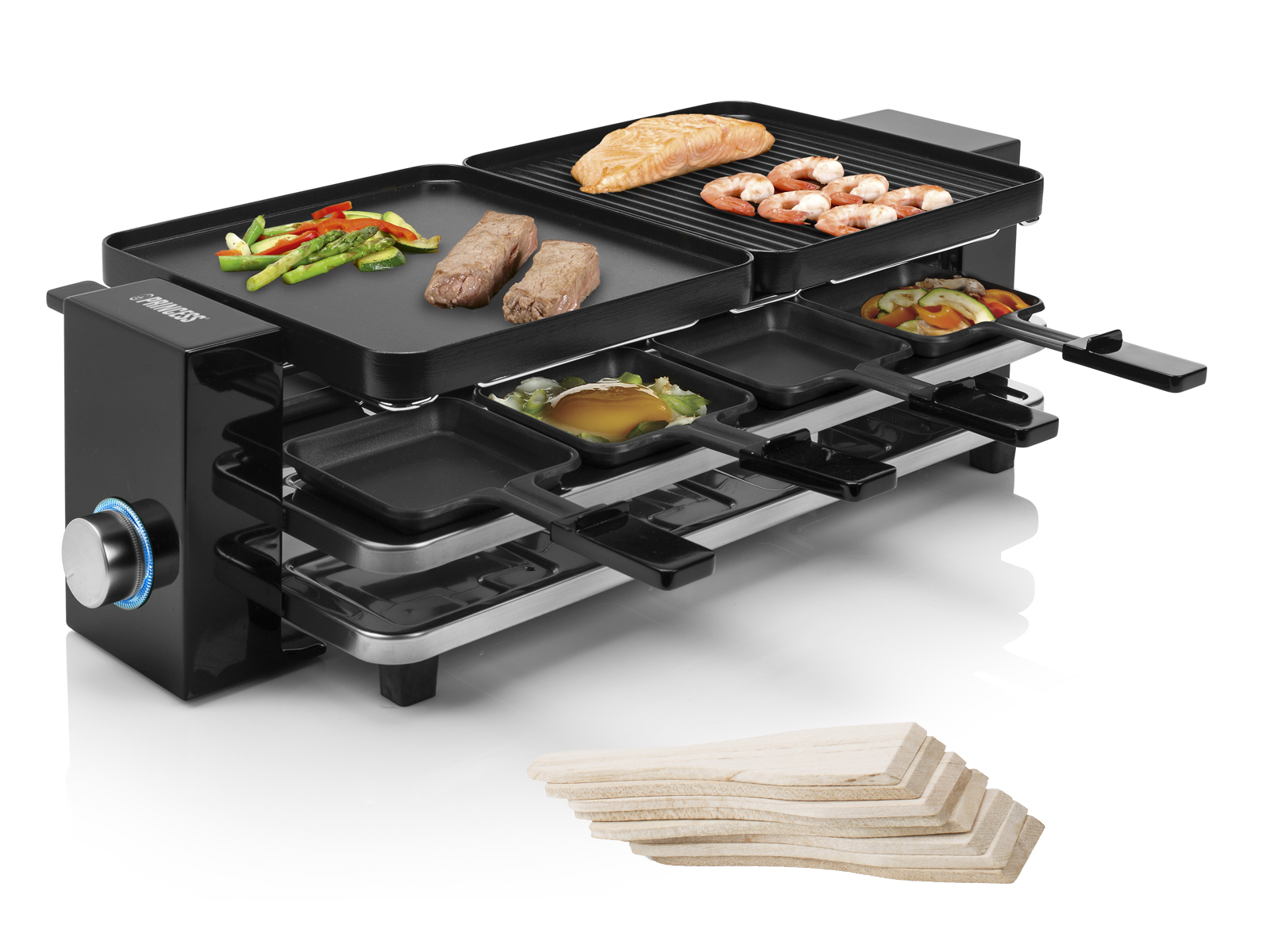 Raclette-Grill mit Speisen auf der Oberfläche und in den Pfannen. Holzspatel im Vordergrund. Drehregler links.