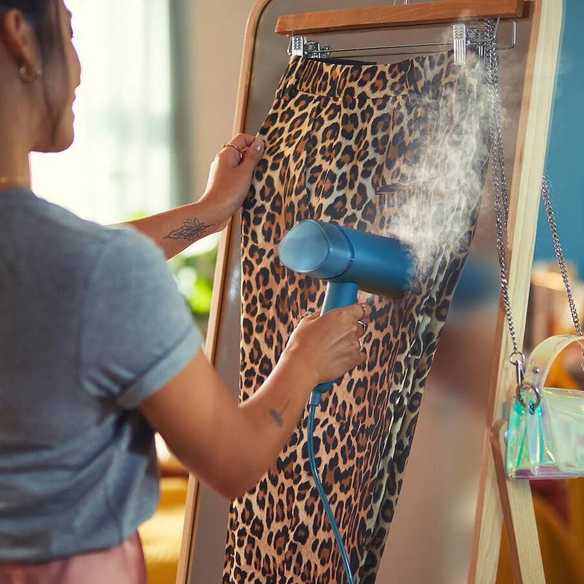 Mujer vaporizando pantalones con estampado de leopardo en un soporte.