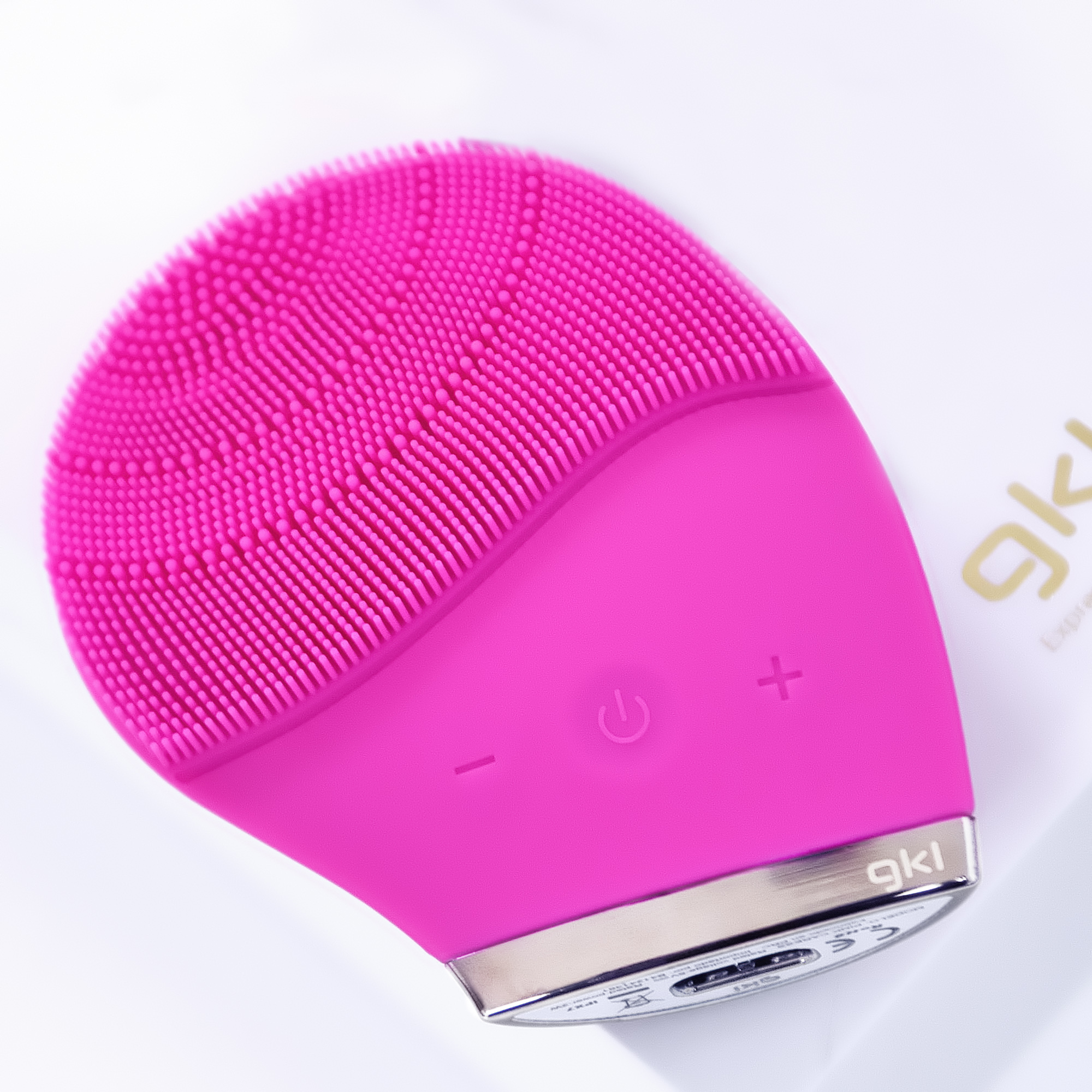 Cepillo de limpieza facial rosa con forma redondeada y pequeñas cerdas.