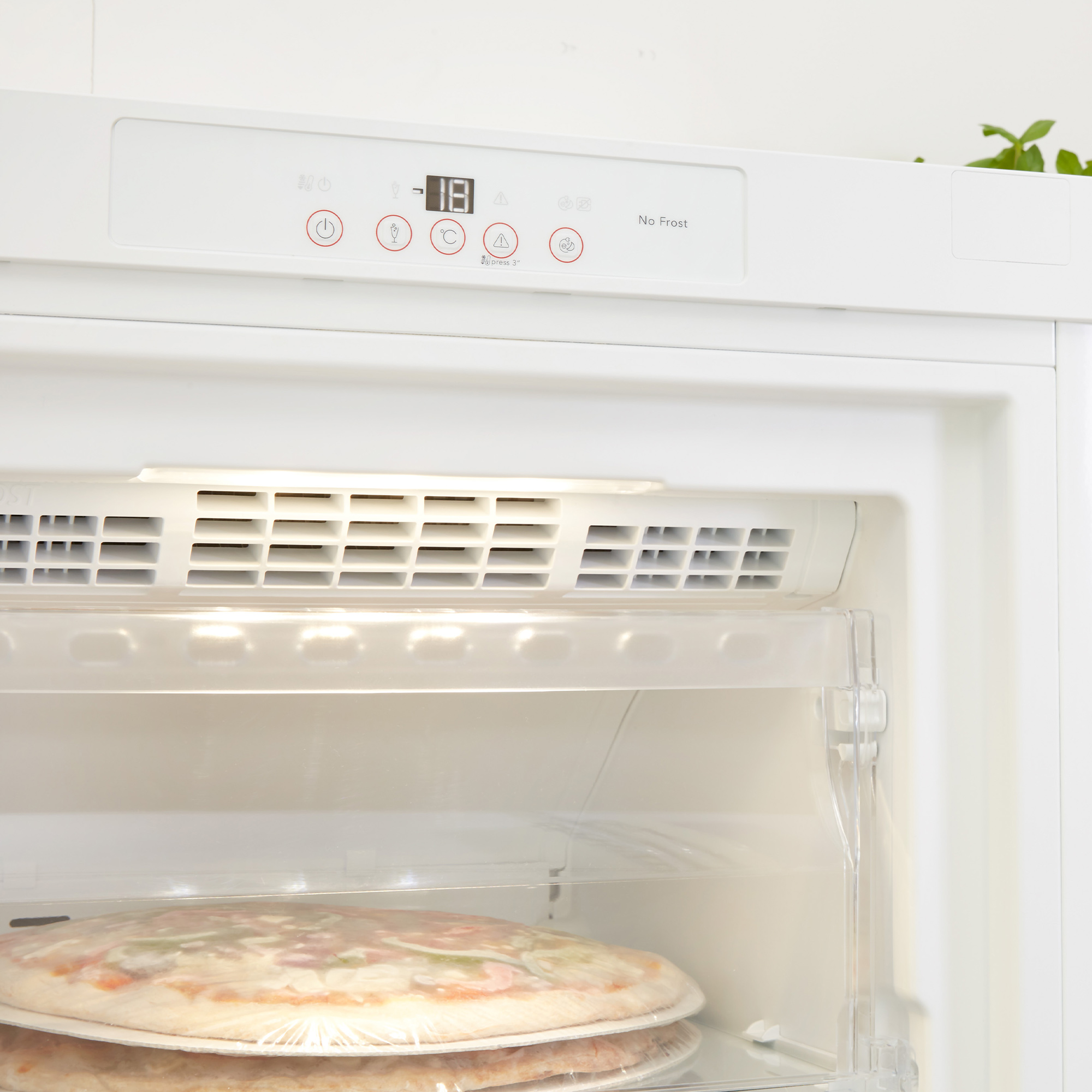 Weißer Kühlschrankinnenraum mit Pizzakartons und Temperaturanzeige oben.