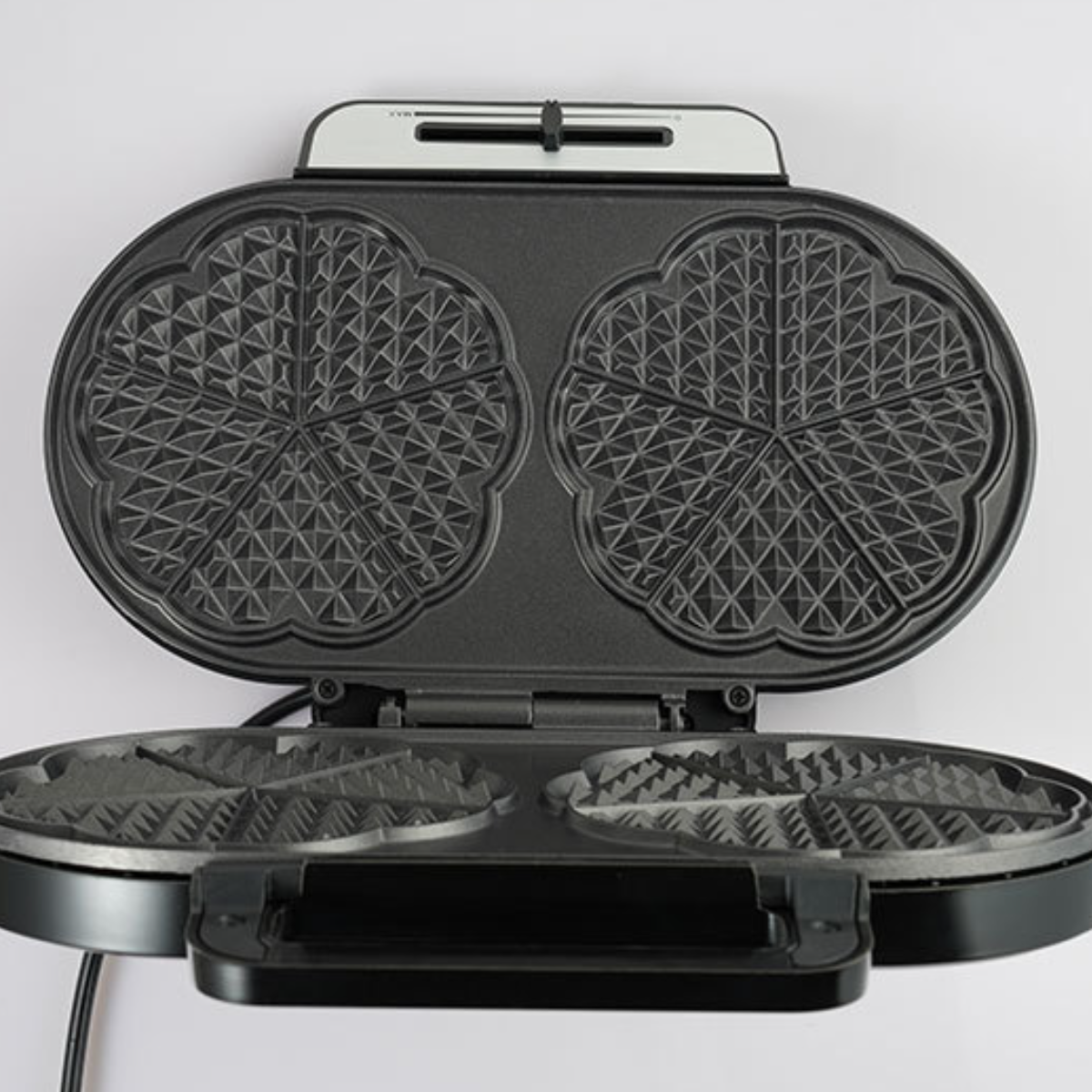 Waffeleisen geöffnet. Zwei Waffelformen sichtbar. Das Eisen ist schwarz mit weißem Hintergrund.