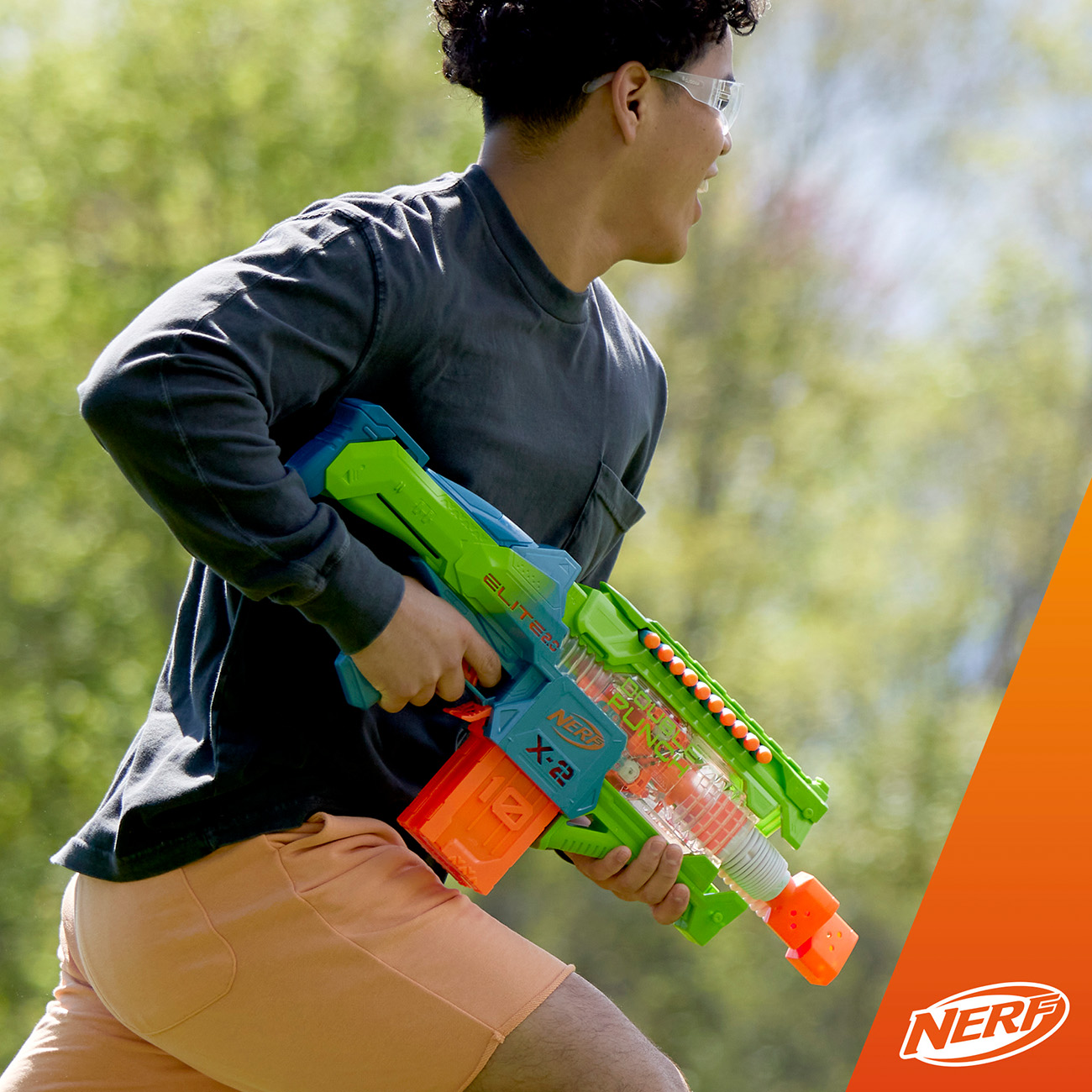 Un giovane corre con un blaster Nerf. Il blaster è blu, verde e arancione.