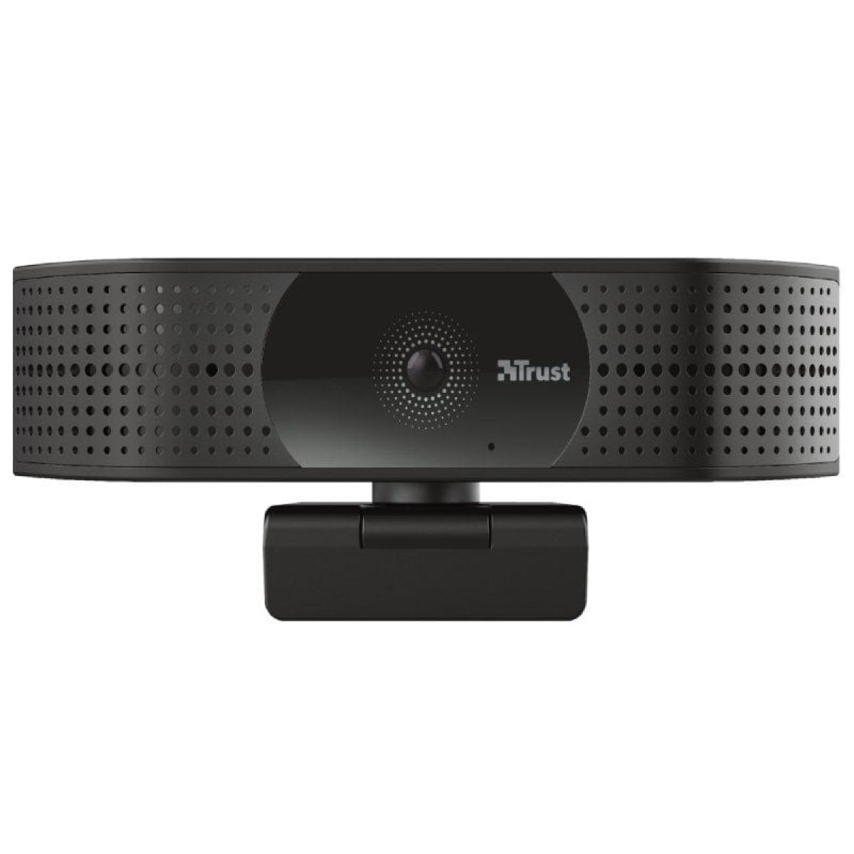 Webcam negra con el logo de Trust. Tiene forma rectangular y un soporte. El frente tiene una lente y agujeros.