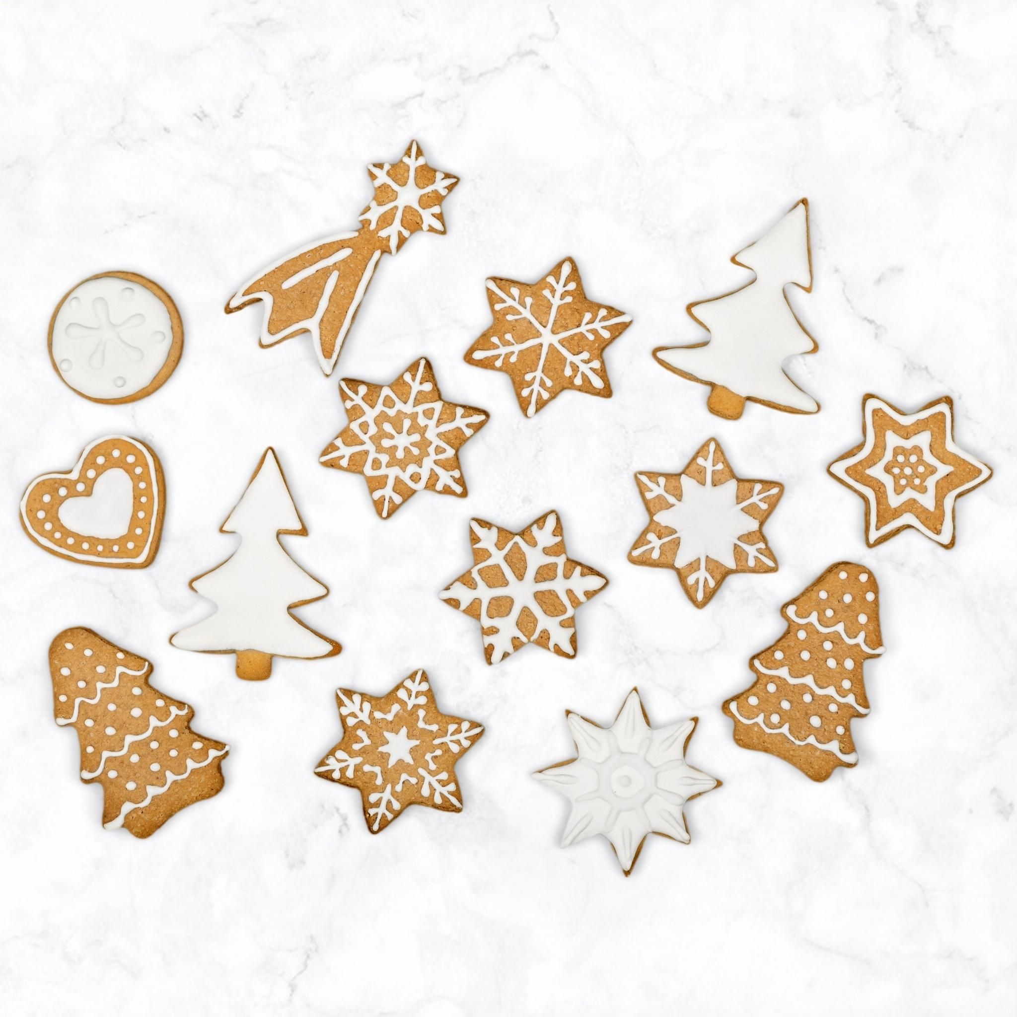 Lebkuchen in verschiedenen Formen: Sterne, Bäume, Kreise, Herzen und Sternschnuppen auf Marmoroberfläche.