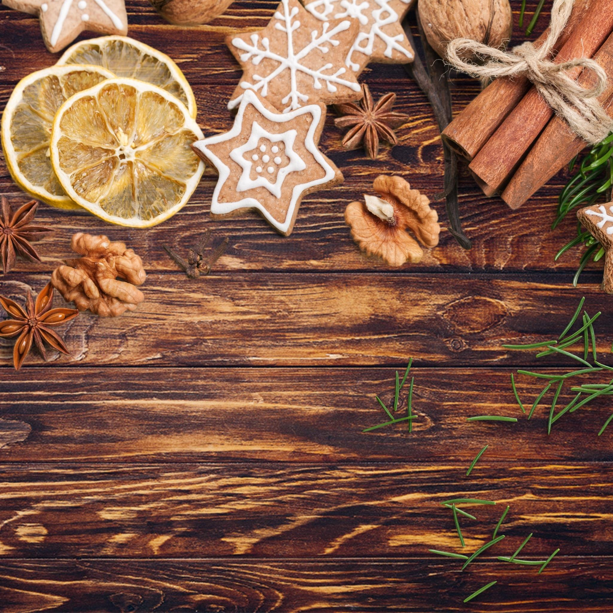 Weihnachtsarrangement mit Keksen, Walnüssen, Zimt und Sternanis auf dunkler Holzoberfläche.