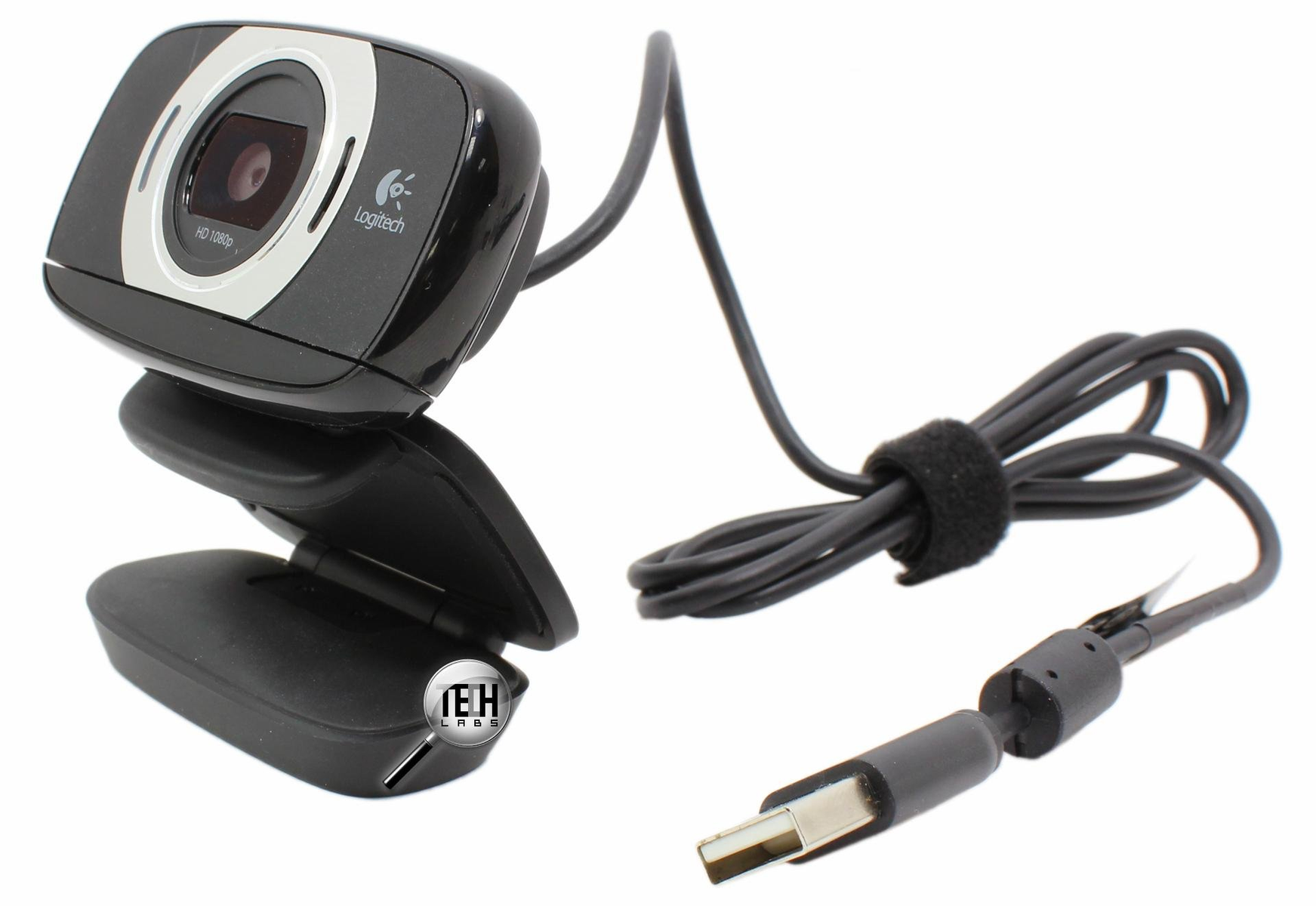 Webcam su sfondo bianco. Ha un corpo nero e un cavo con connettore USB.