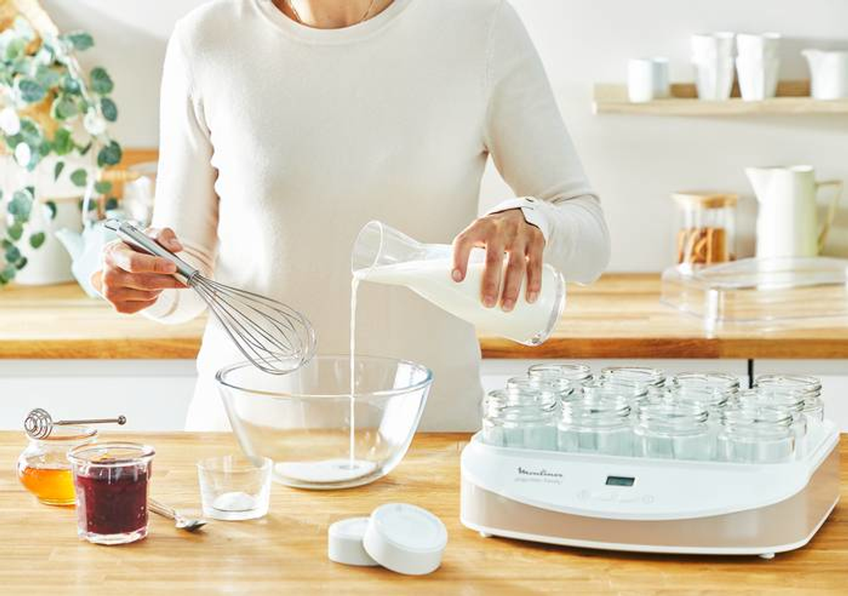 Una persona versa il latte in una ciotola, preparando una ricetta con ingredienti vicini.