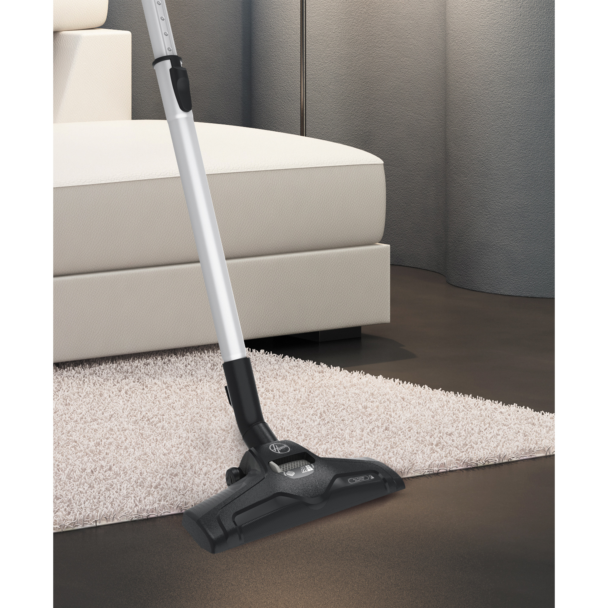 Odkurzacz na białym dywanie. Biała sofa w tle. Ciemna podłoga.