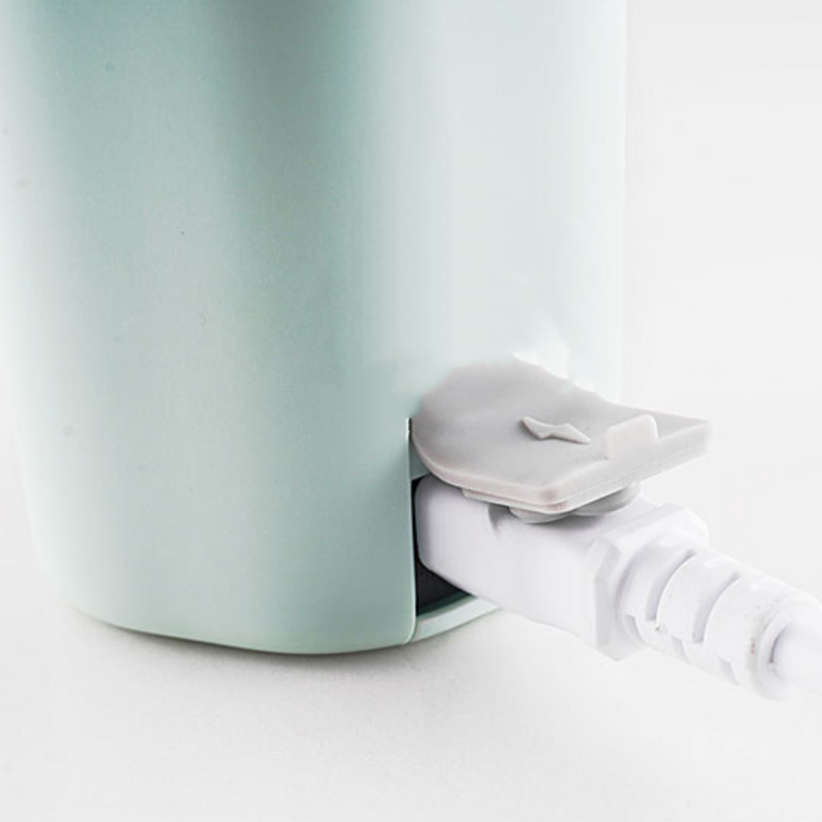 Nahaufnahme eines hellen türkisblauen Geräts mit einem weißen Ladekabel.