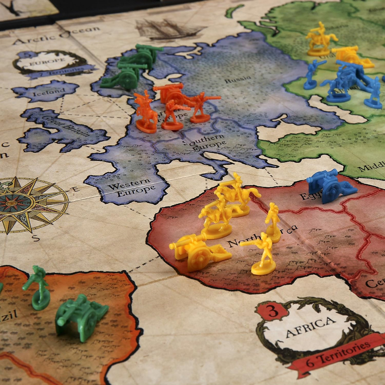 Brettspiel mit farbigen Spielfiguren auf einer Karte, die Kontinente, Meere und Gebiete zeigt.