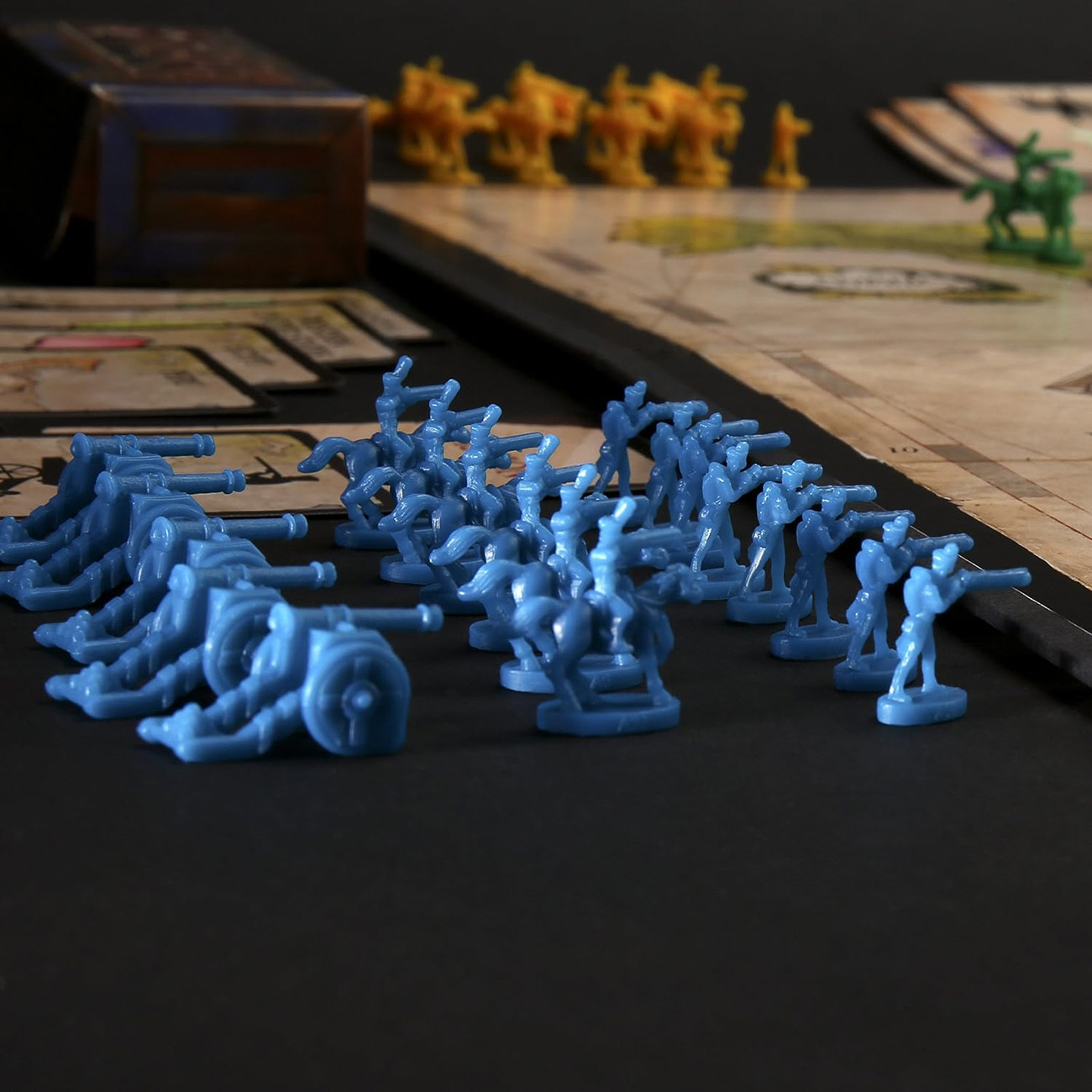 Une scène de jeu de société avec des figurines de l'armée bleue, des figurines jaunes et des figurines vertes avec un plateau de jeu en arrière-plan.