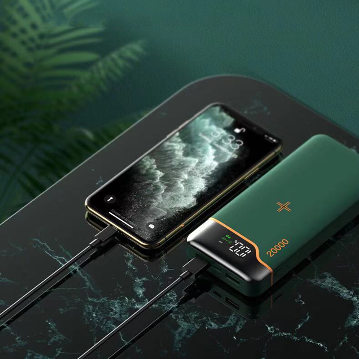 Ein Smartphone, das von einer grünen Powerbank auf einer schwarzen Marmoroberfläche geladen wird.