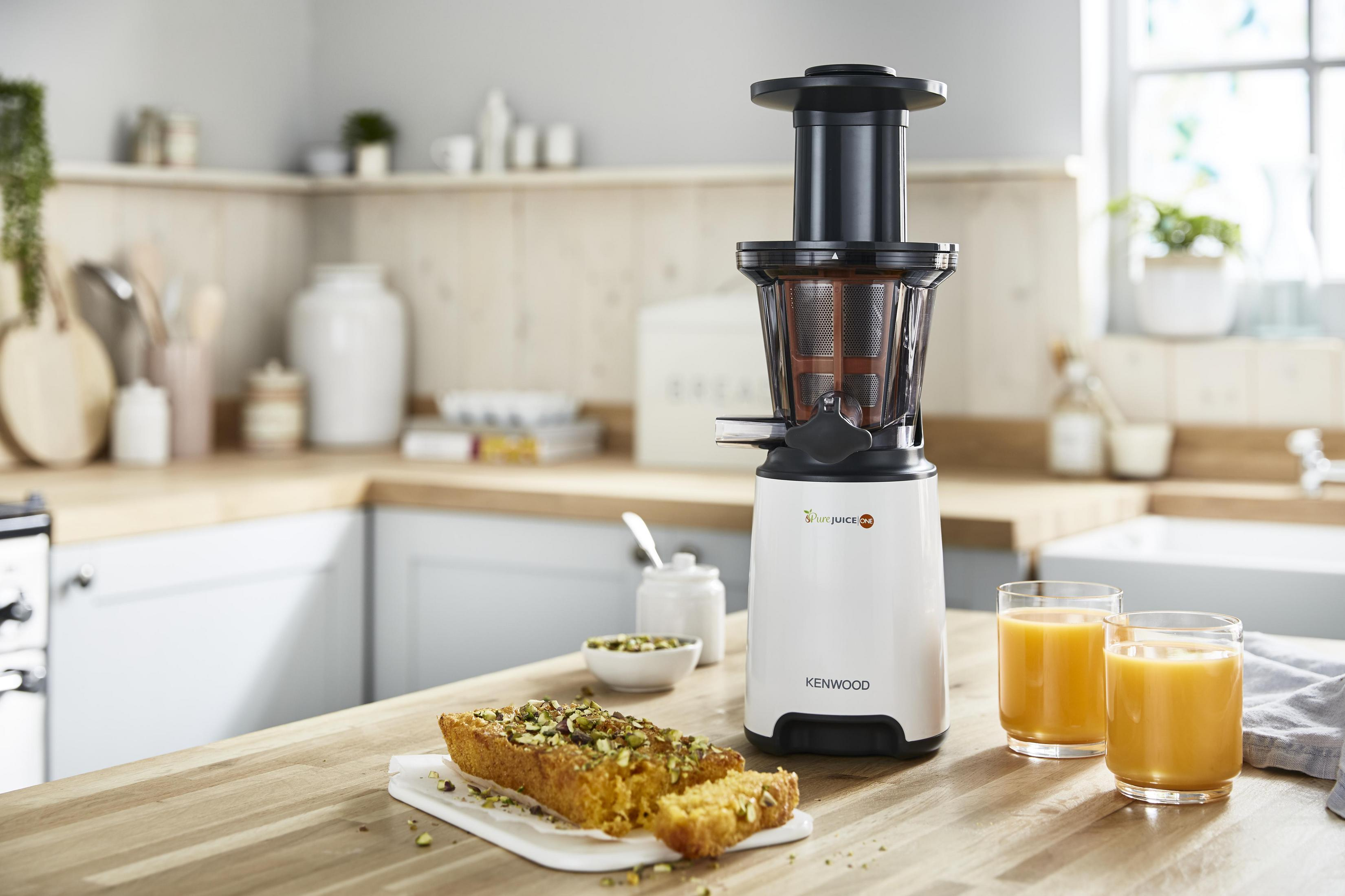 Scena kuchenna z wyciskarką do soku. Ciasto i sok w szklankach na blacie. Tło pokazuje kuchnię.