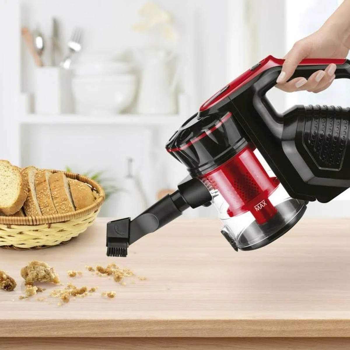 Una aspiradora limpiando migas de una mesa de madera. Pan en cesta, fondo blanco.