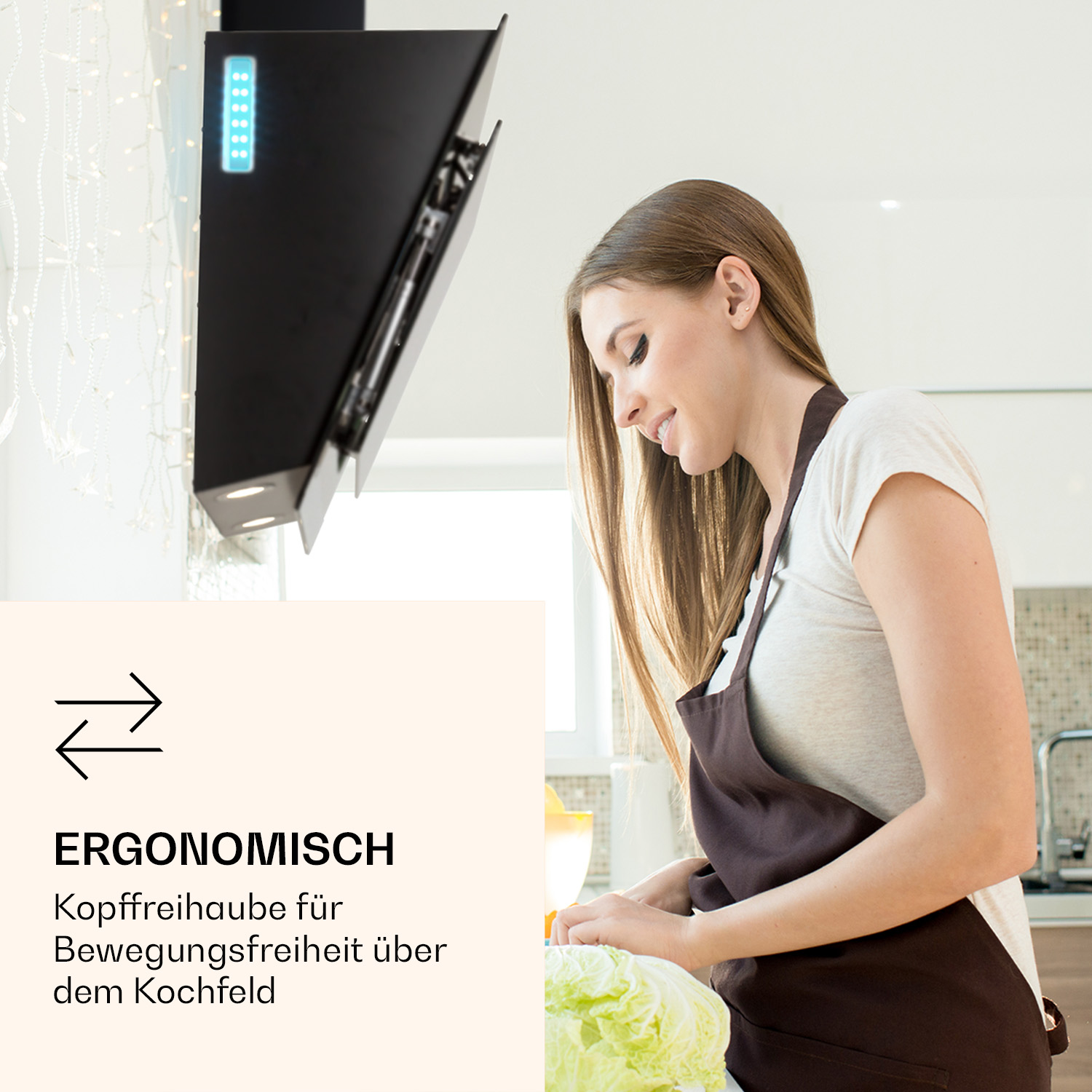 Eine Frau in einer Küche, die Essen zubereitet, mit einer schwarzen Dunstabzugshaube und einer weißen Wand im Hintergrund.