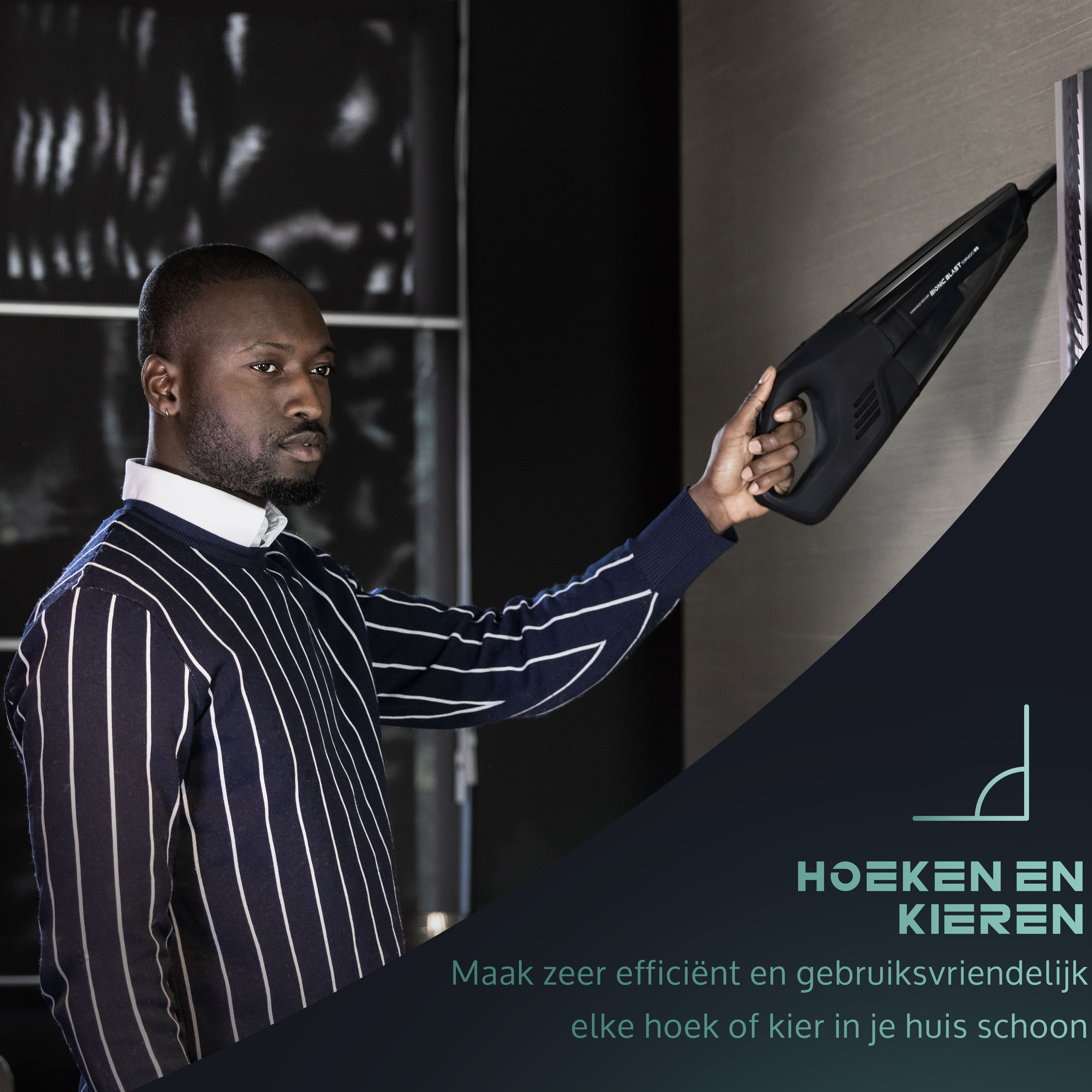 Man using a black handheld vacuum on a wall. Text reads: HOEKEN EN KIEREN, clean every corner.