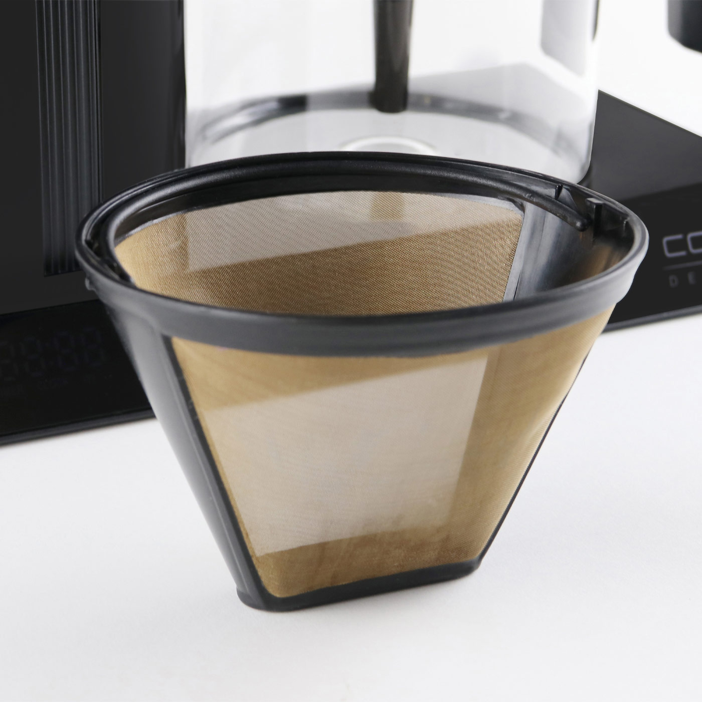 Nahaufnahme eines Kaffeefilters, schwarzer Rahmen, hellbraunes Netz, weißer Hintergrund.