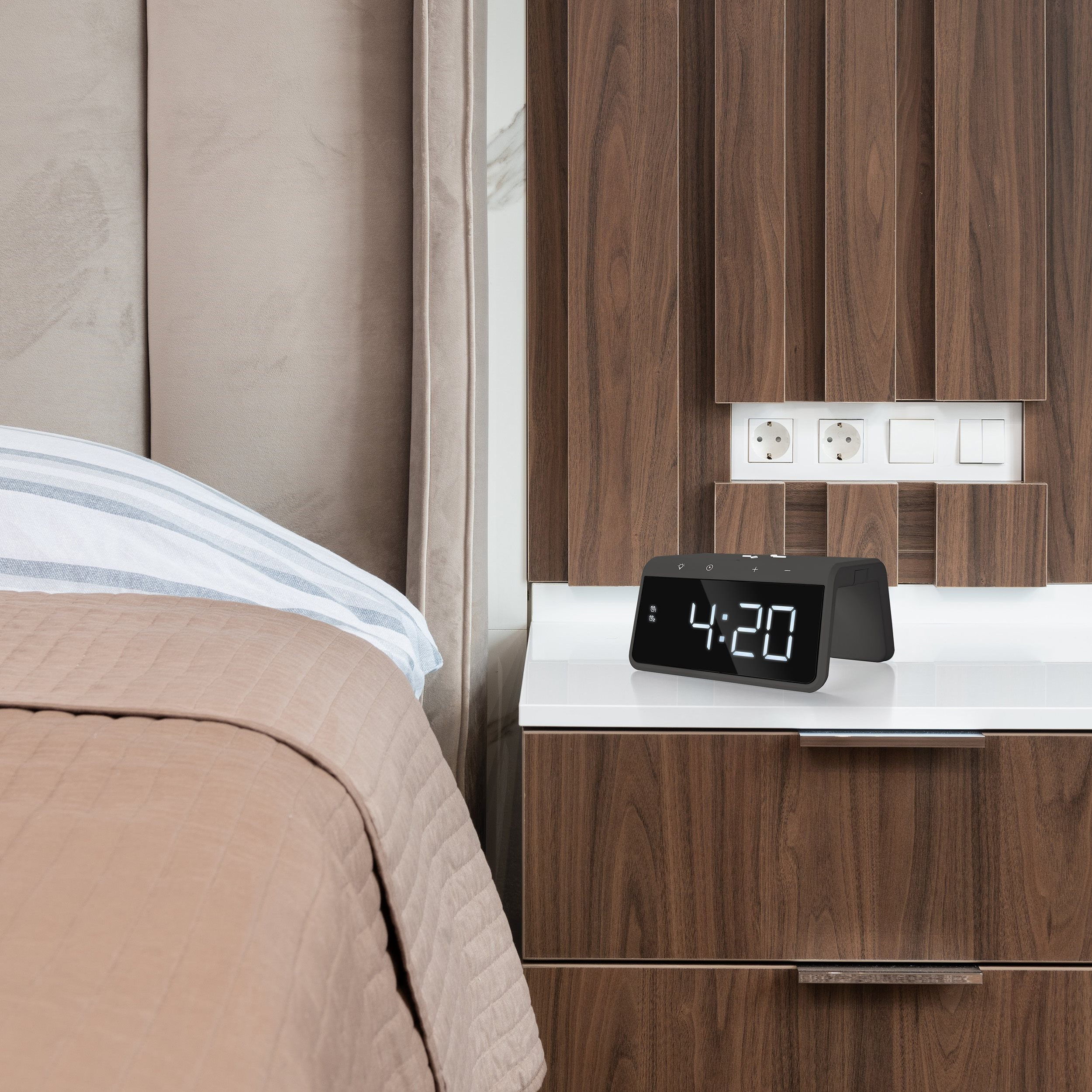 Bedroom nightstand with a clock displaying 4:20. The bed has a comforter and pillow, dark wood paneling.