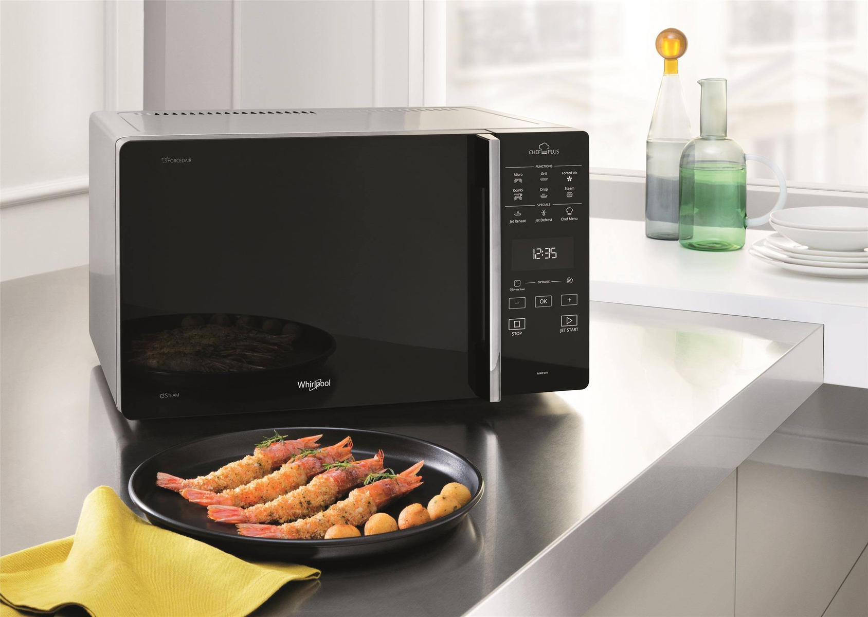 Czarna kuchenka mikrofalowa na blacie z jedzeniem, tłem okna i żółtą serwetką.