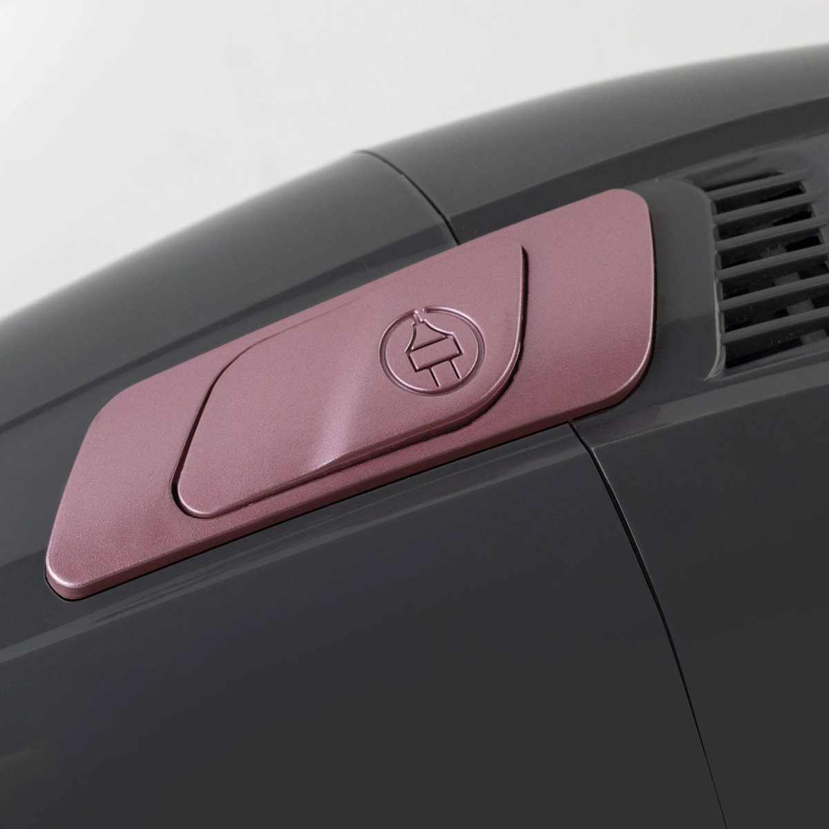 Primer plano de una aspiradora gris oscuro con un panel de acento color oro rosa.
