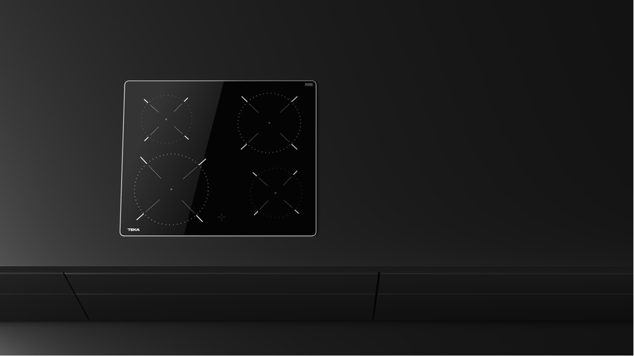 Czarna płyta grzewcza na blacie, z czterema okrągłymi strefami gotowania, z logo Teka.