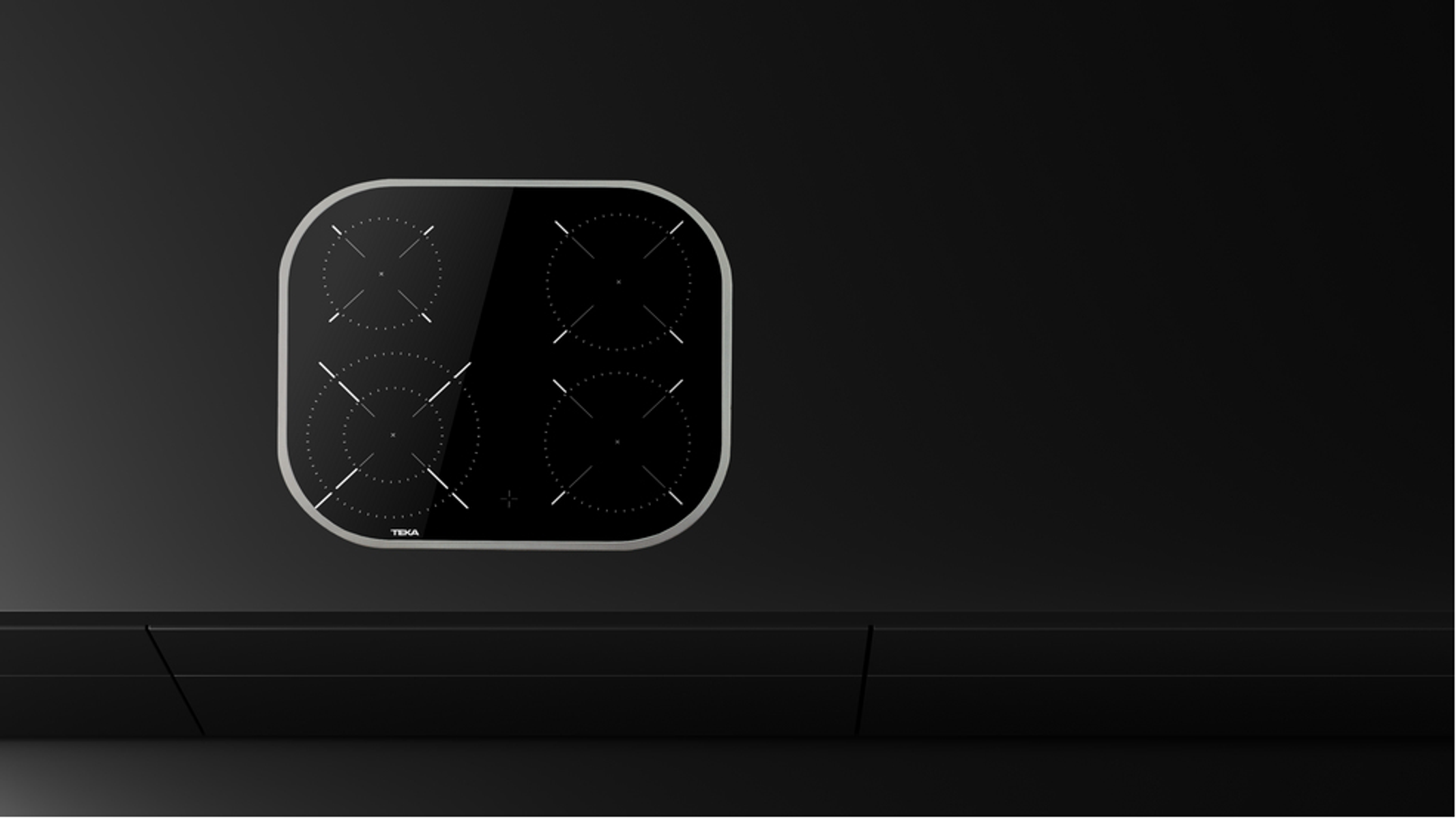 Czarna płyta grzewcza ze szkła na czarnej powierzchni. Widoczne cztery okrągłe elementy palników.