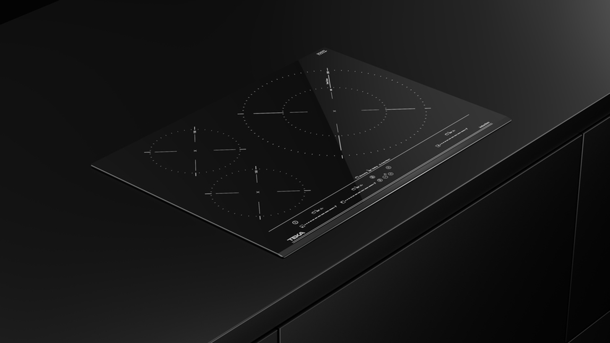 Czarna płyta indukcyjna z czterema palnikami na czarnym blacie. Ciemne tło.