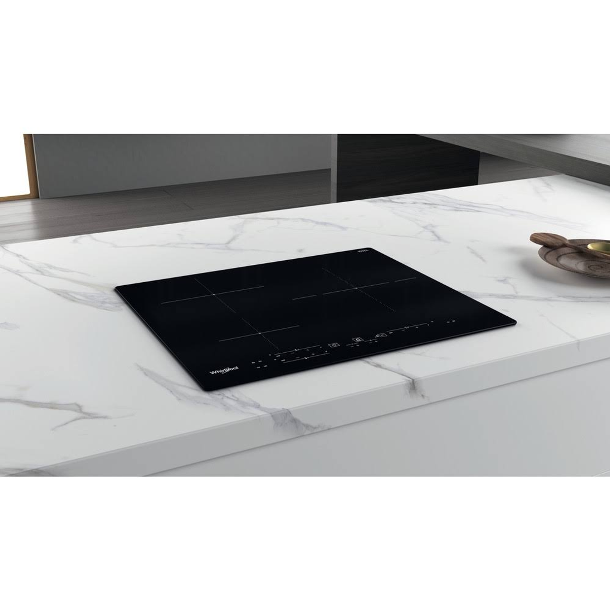 Placa de inducción negra sobre encimera de mármol blanco, con el logo de Whirlpool.