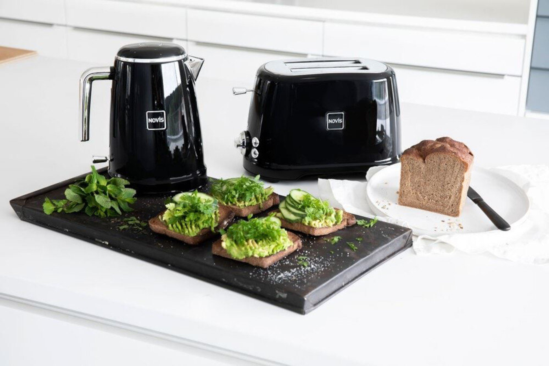 Ein schwarzes Wasserkocher- und Toaster-Set mit Avocado-Toast und Brot.