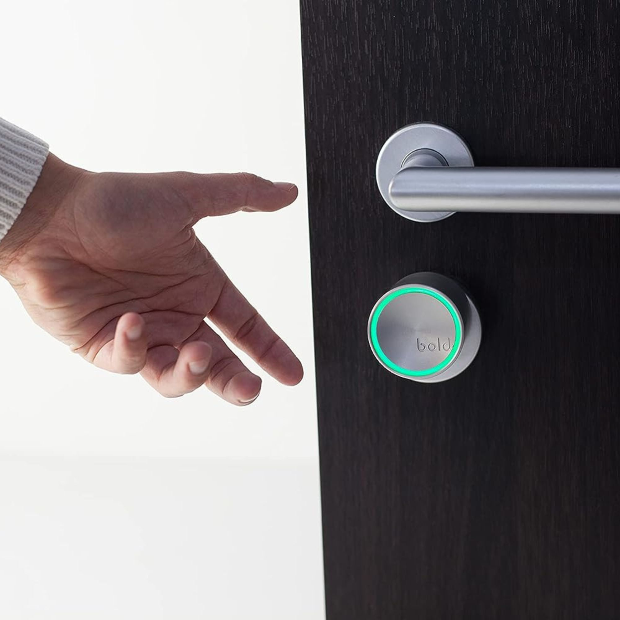 La mano de una persona se acerca a una cerradura inteligente en una puerta oscura con una luz verde.