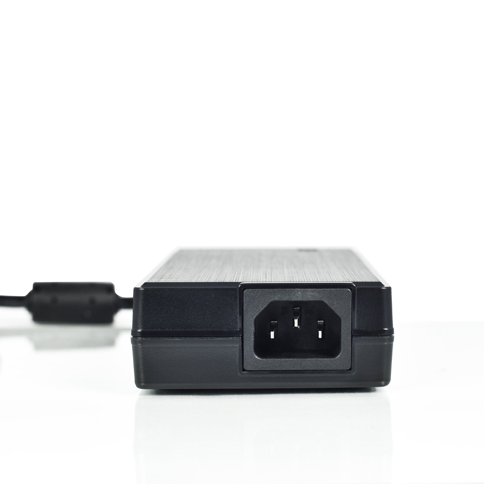 Ein schwarzes Netzteil mit Stecker auf weißer Oberfläche. Der Stecker hat drei Löcher.
