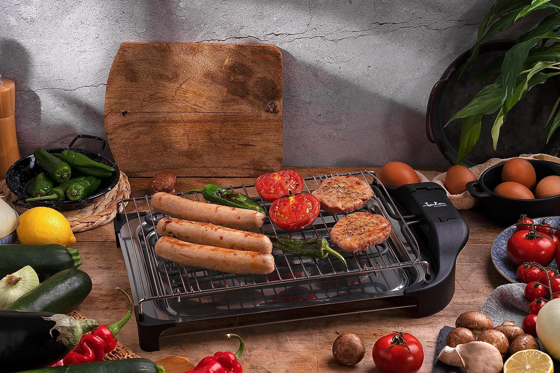 Una griglia con cibo grigliato su un tavolo di legno. La scena include pomodori, salsicce e peperoni.