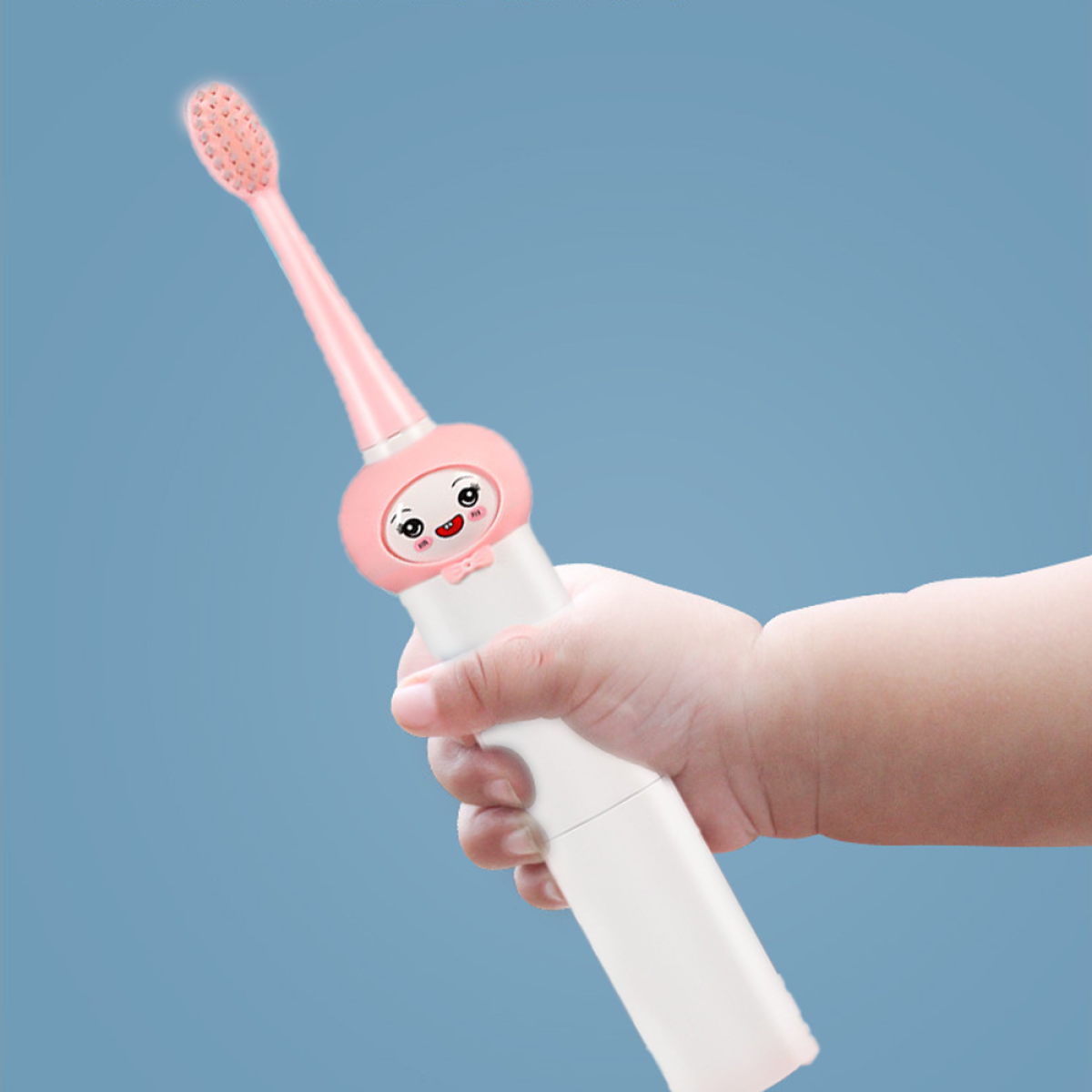 Kinderhand hält eine rosa elektrische Zahnbürste mit einem Cartoon-Gesicht darauf.