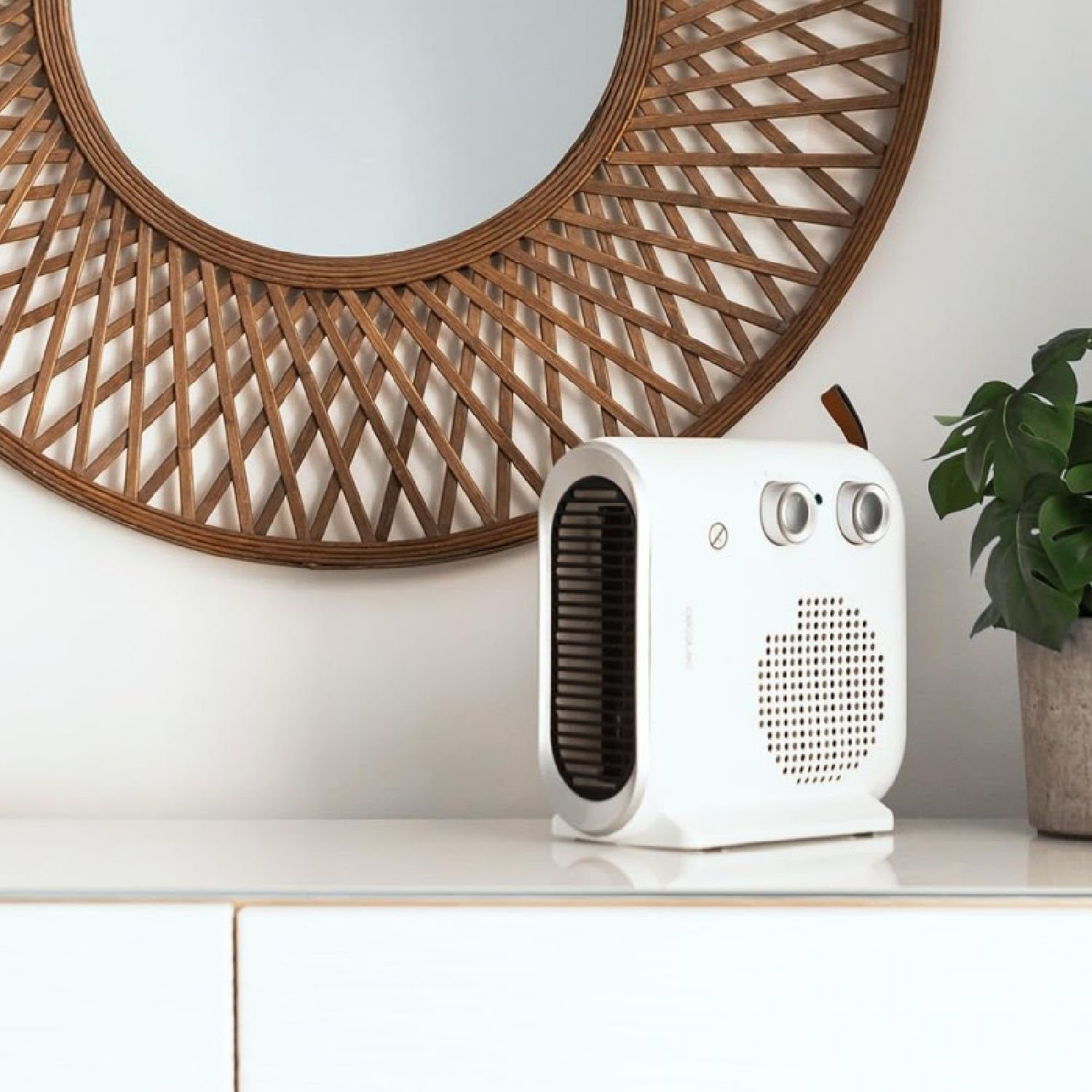 Termoventilatore elettrico bianco su superficie bianca, con specchio rotondo sullo sfondo.