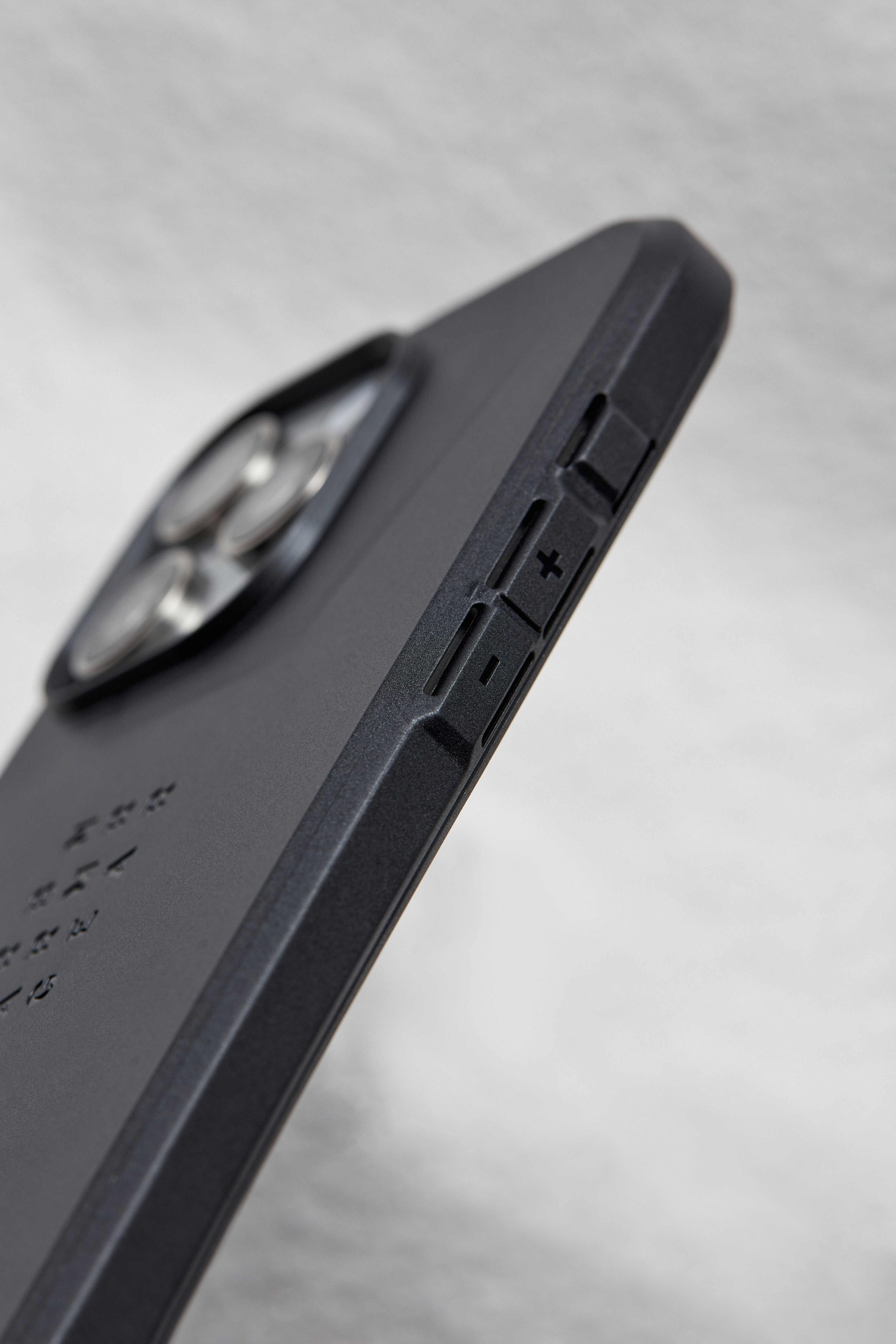 Primer plano de una funda negra para teléfono, mostrando los botones laterales y la cámara.