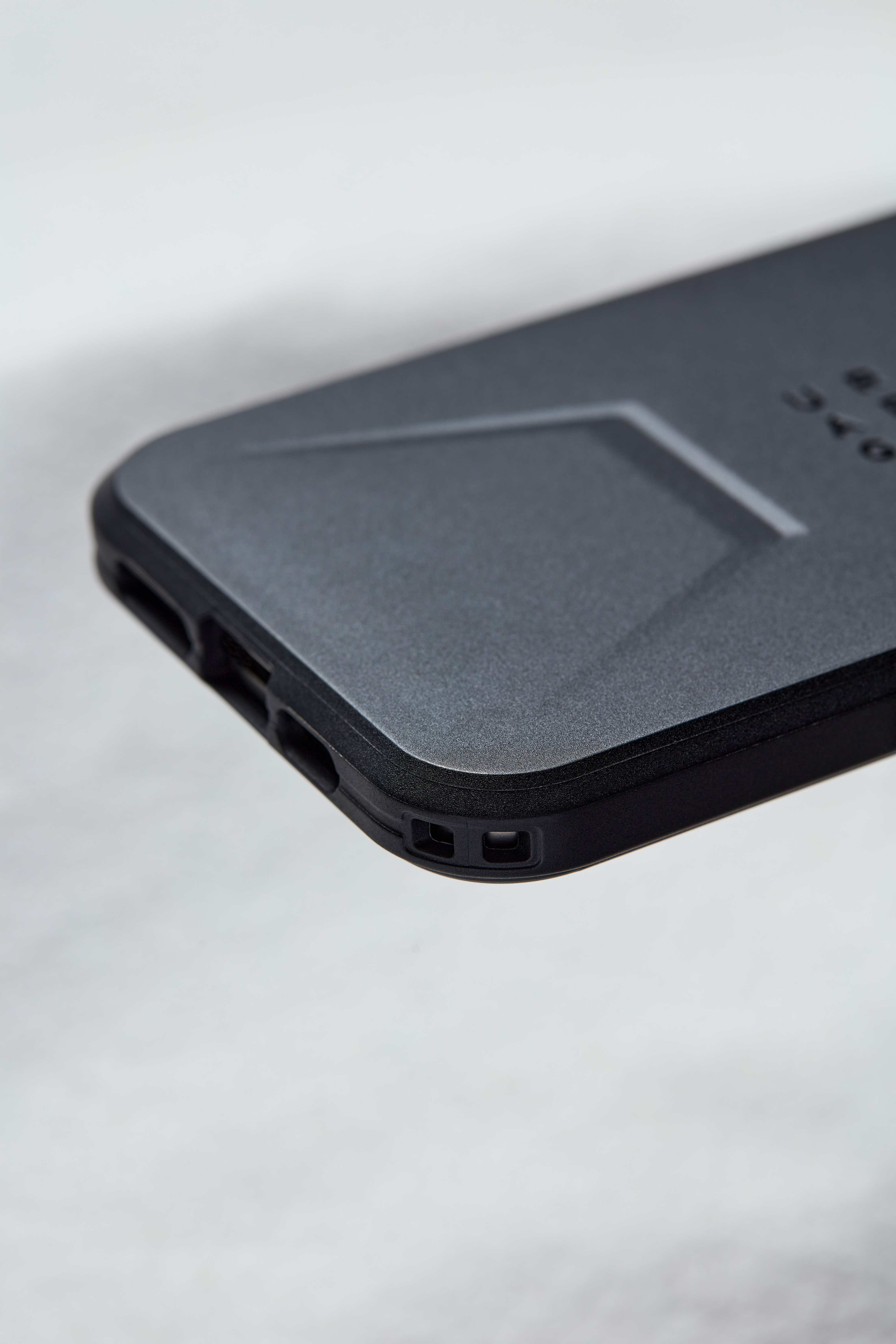 Primer plano de una funda de teléfono gris oscuro con superficie texturizada y bordes negros.