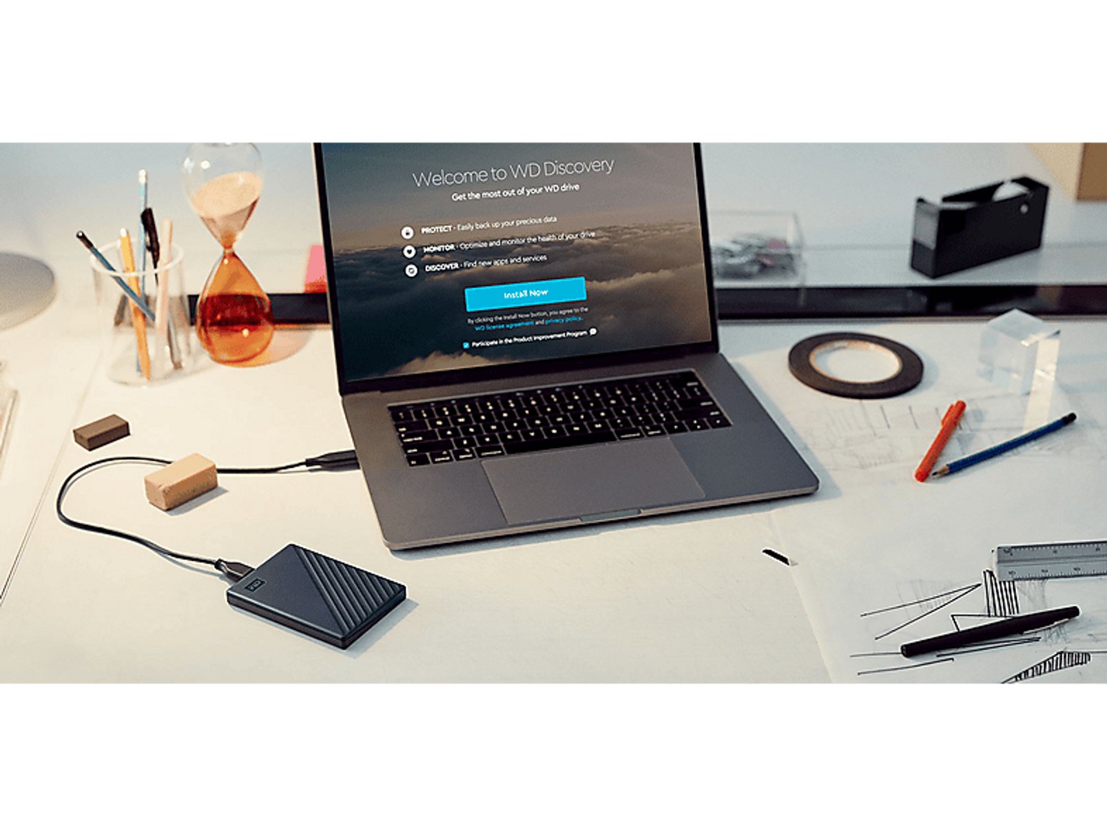 Laptop z ekranem WD Discovery. Podłączony dysk twardy i akcesoria na stole.