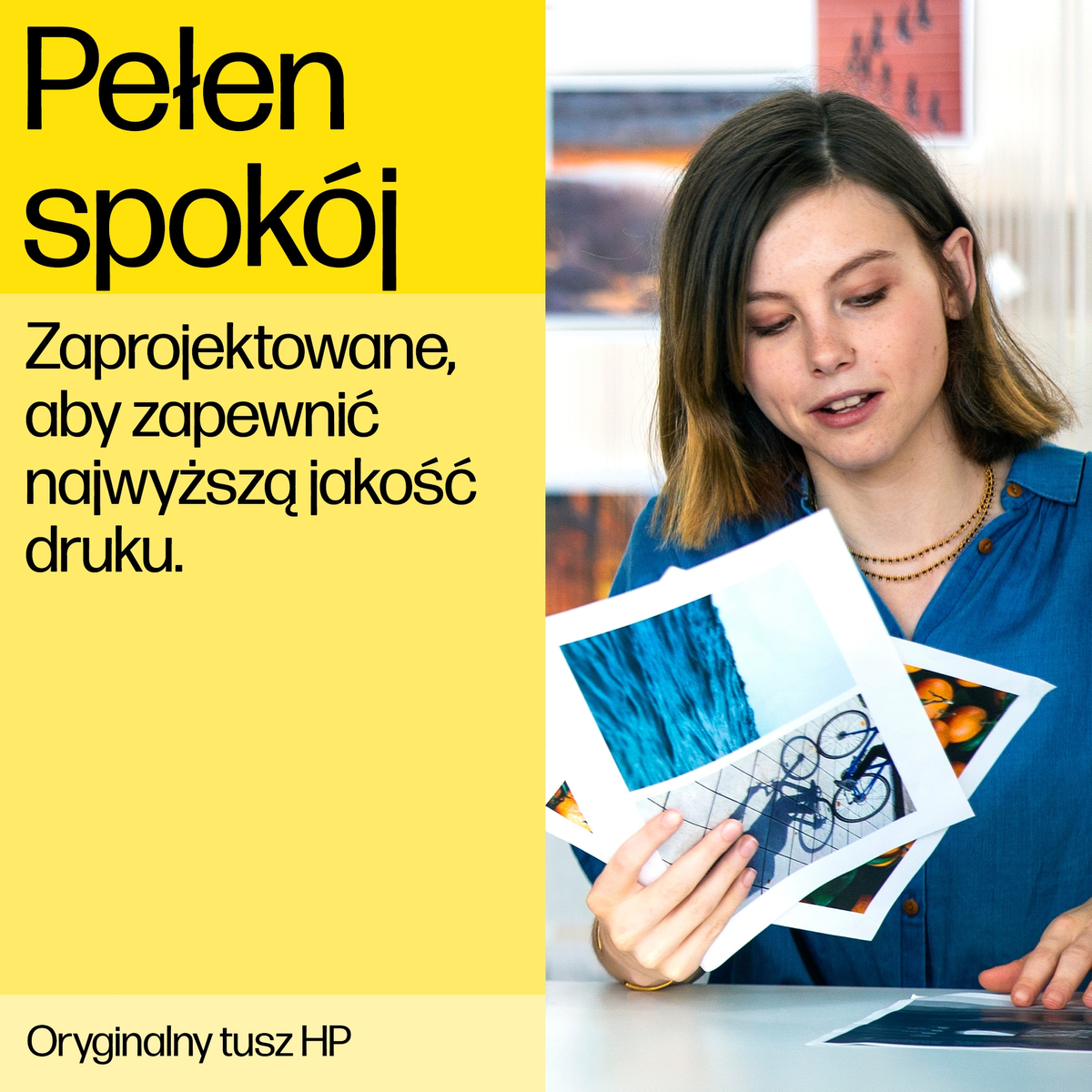 Kobieta trzyma zdjęcia. Ma na sobie niebieską koszulę i patrzy na obrazy.