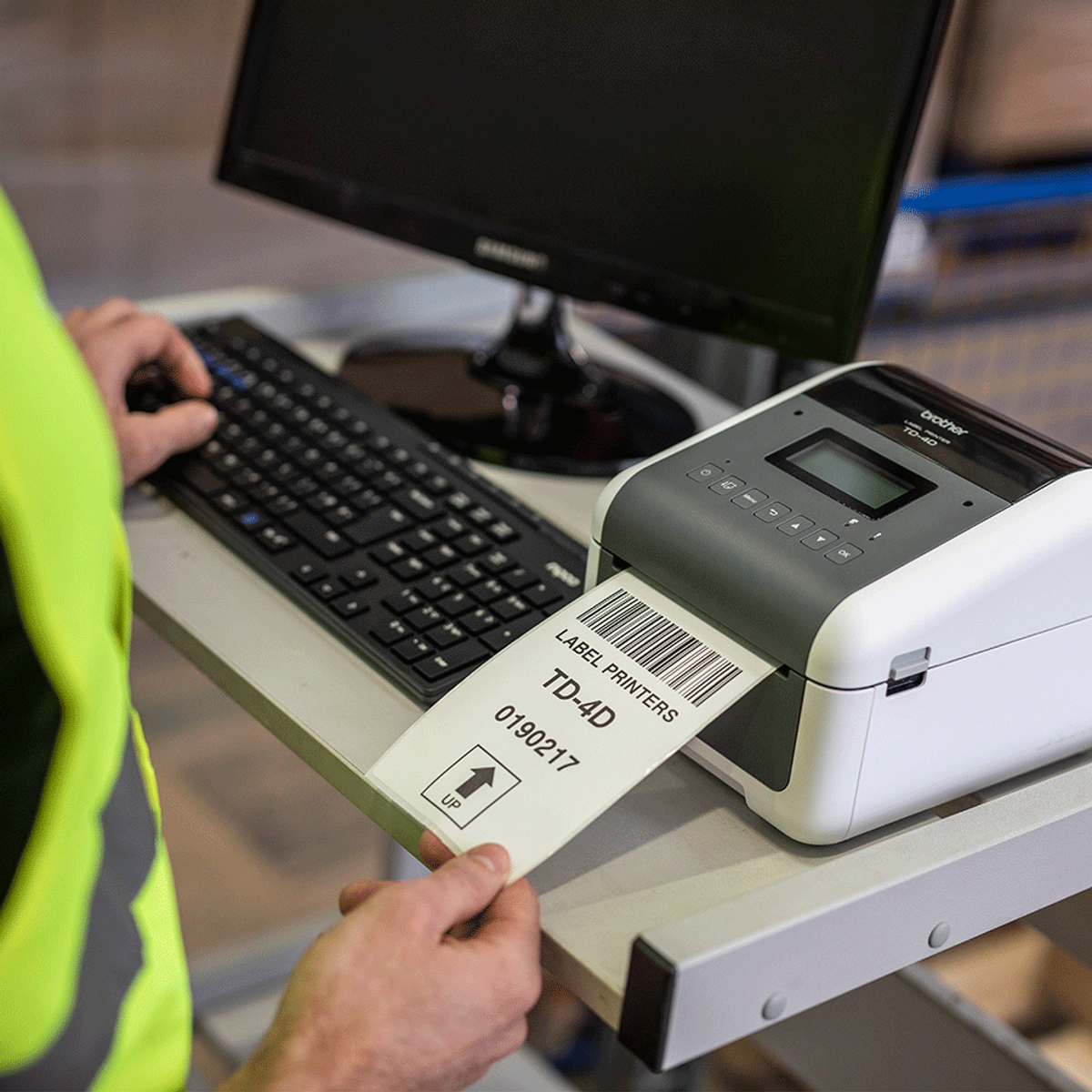 Osoba używająca klawiatury i drukarki etykiet, drukująca etykietę z kodem kreskowym i tekstem.