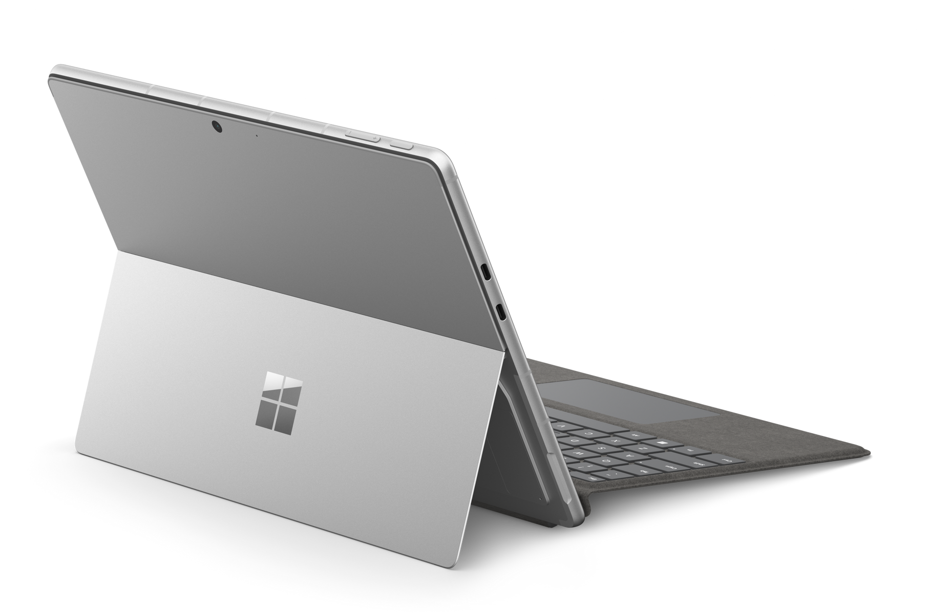 Laptop argentato con schermo aperto, mostra il logo Microsoft. Sfondo nero con punti luce.