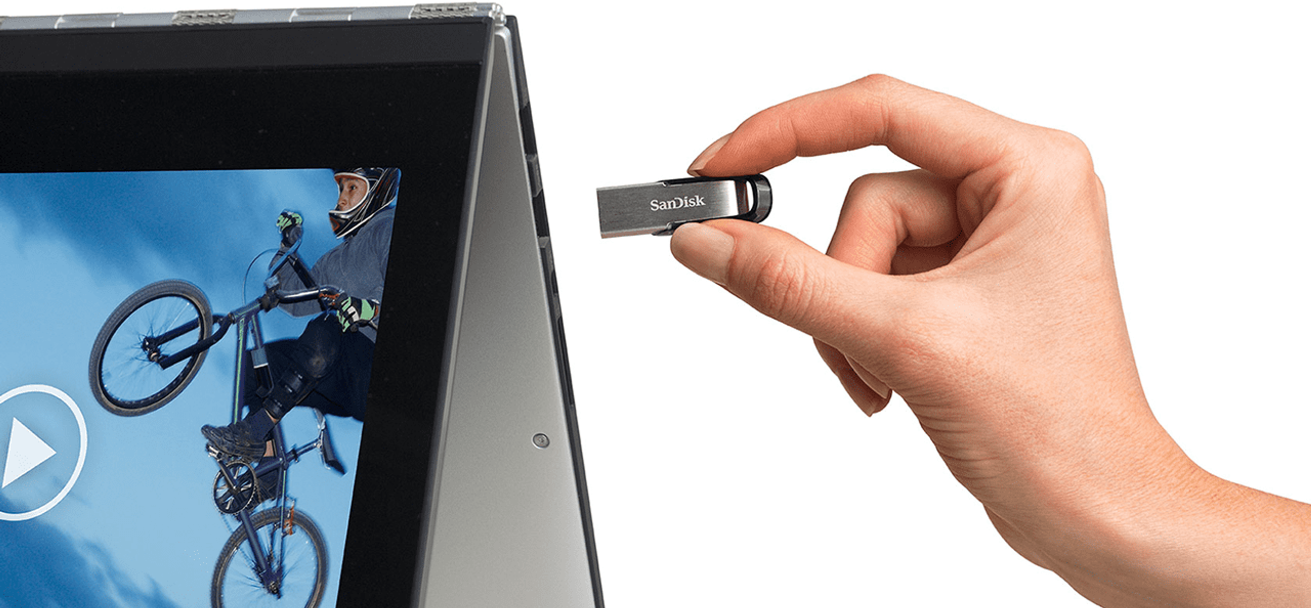 Dłoń trzymająca srebrny pendrive w pobliżu laptopa z kolarzem.