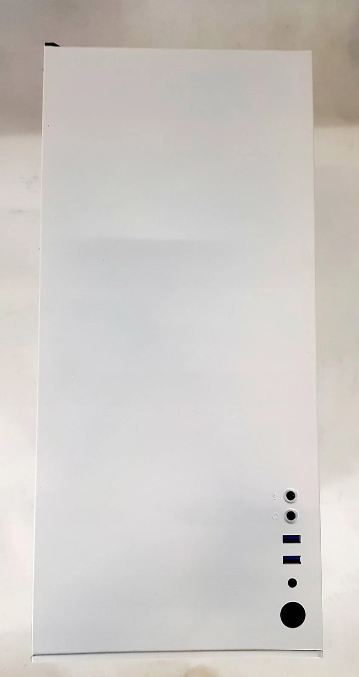 Biała obudowa komputera. Ma kilka portów na dole. Białe tło.