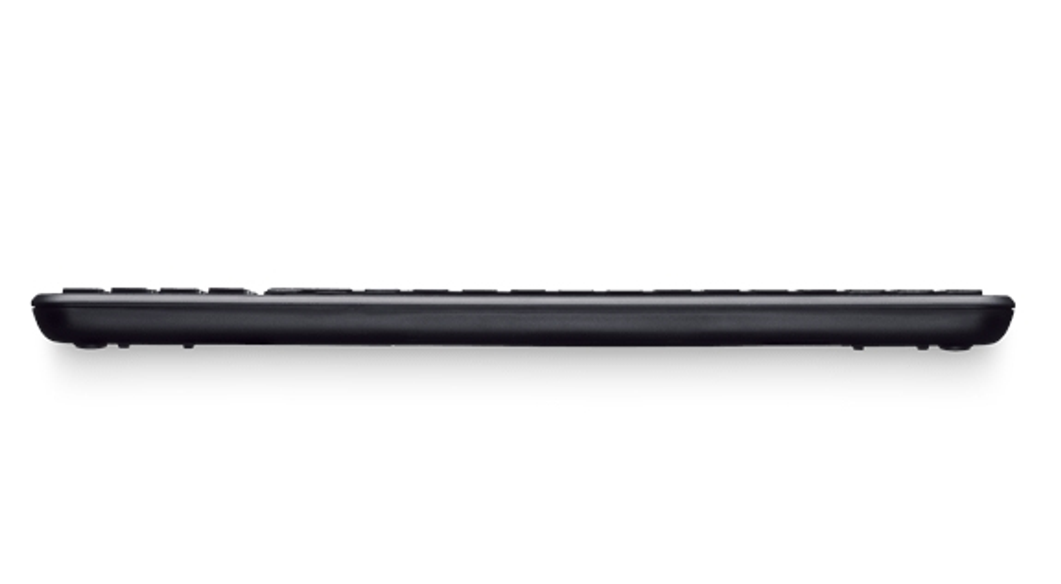 Eine schwarze Tastatur, von der Seite betrachtet, auf einer weißen Oberfläche. Sie ist lang und dünn.