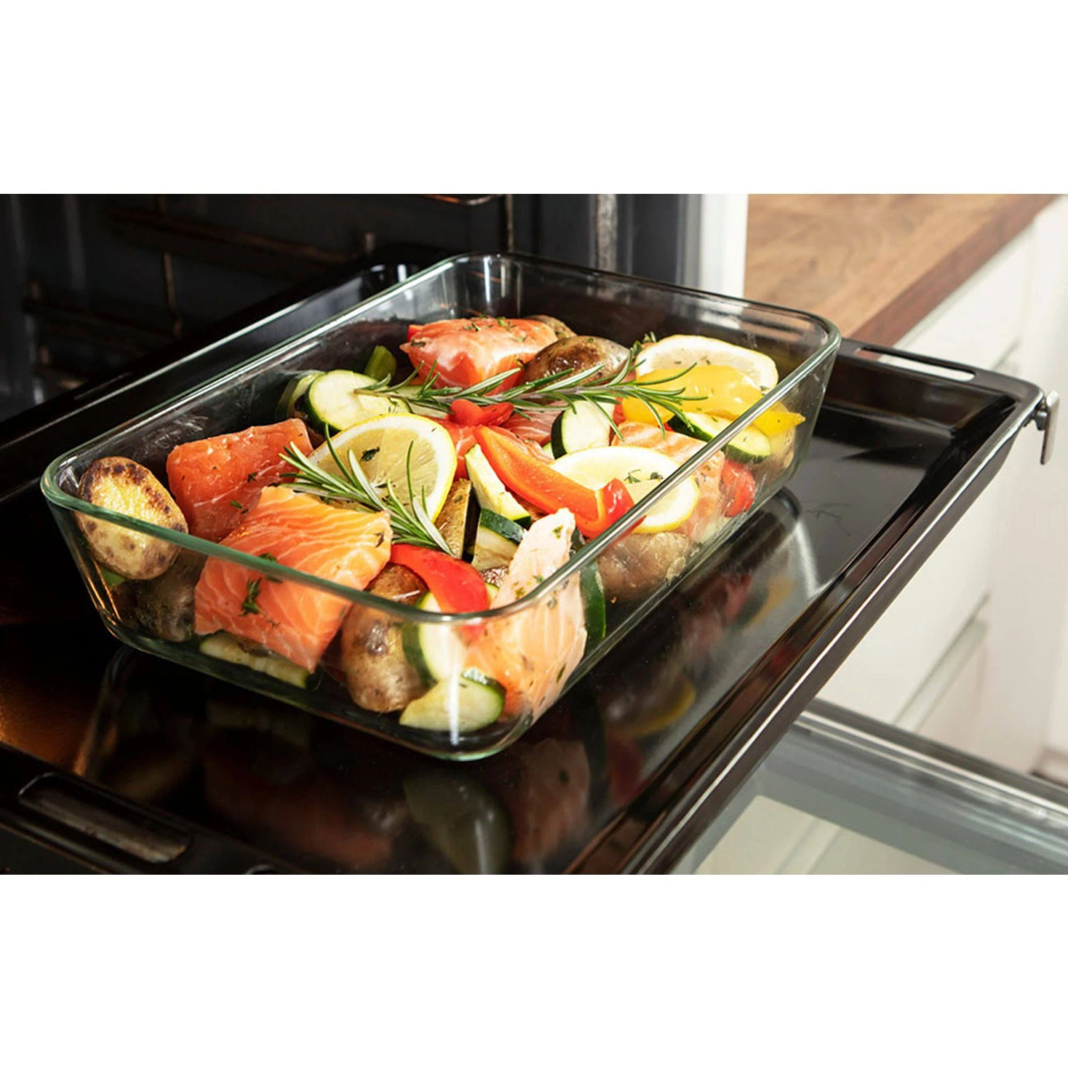Glasform mit Lachs, Gemüse und Zitronenscheiben im Ofen.